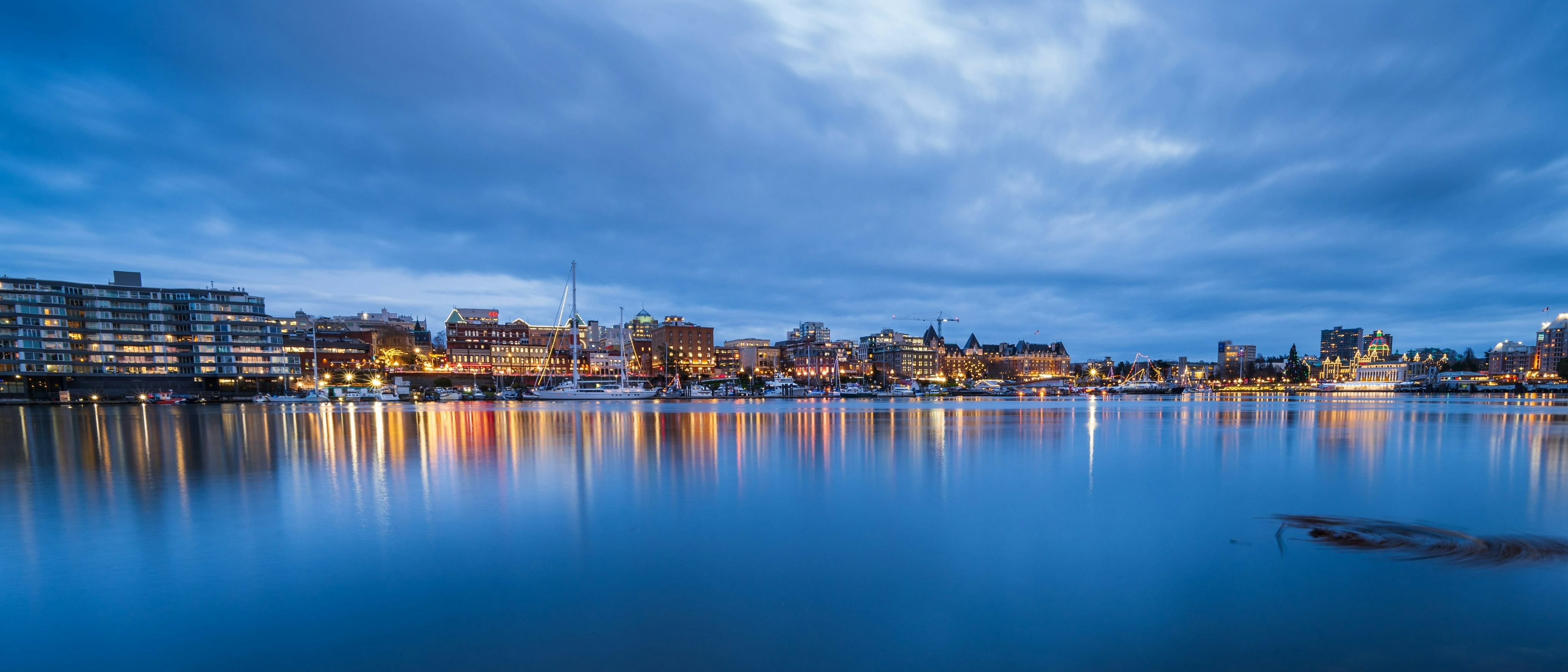 Victoria Harbour in British Columbia, Canada, bathed in evening light with reflections shimmering on the water.