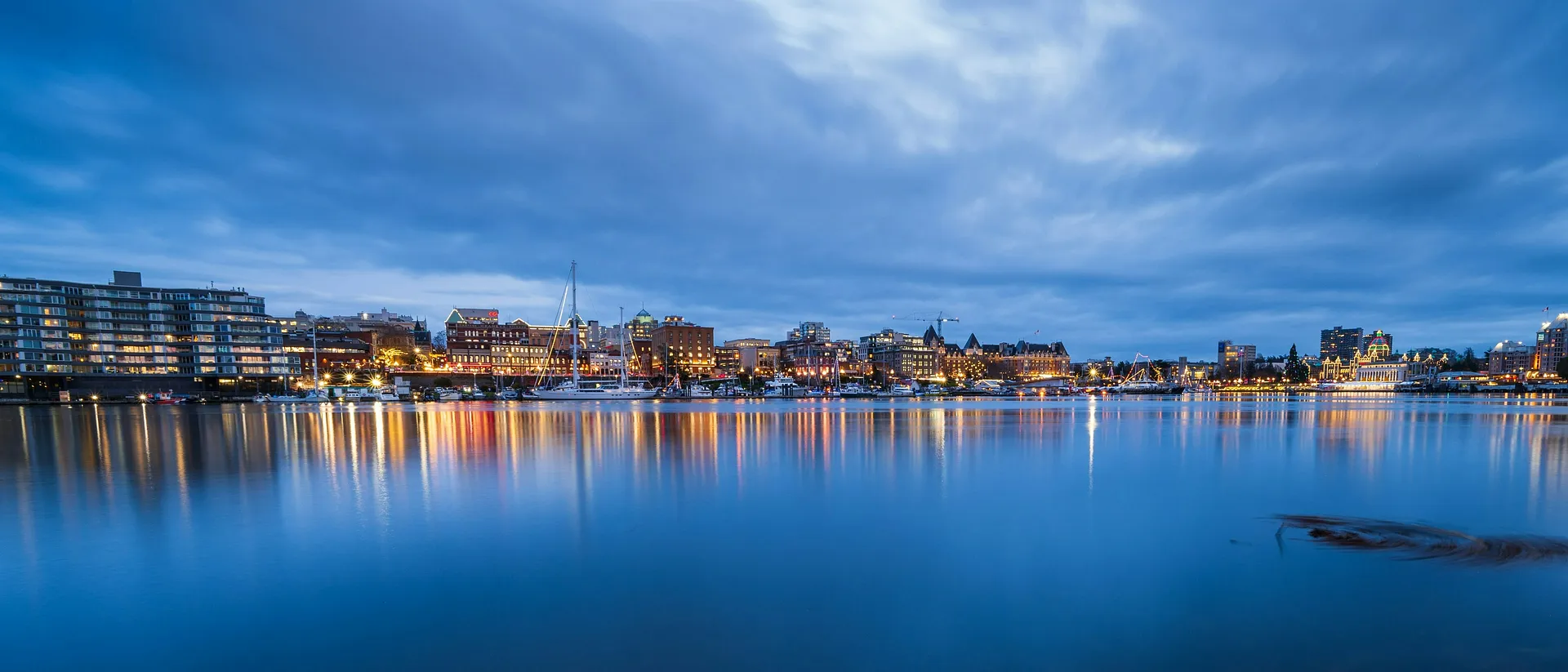 Victoria Harbour in British Columbia, Canada, bathed in evening light with reflections shimmering on the water.