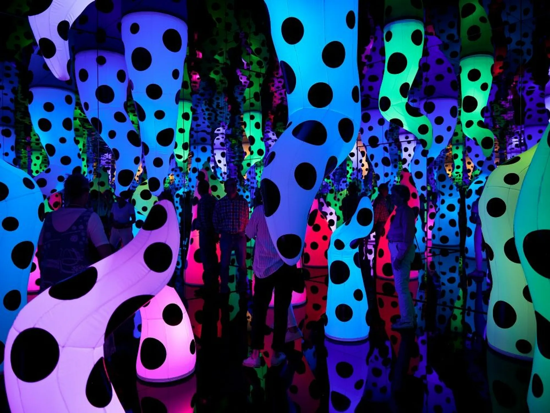 A vibrant, polka-dotted installation at Yayoi Kusama's exhibit in New York mirrors endless colorful shapes.