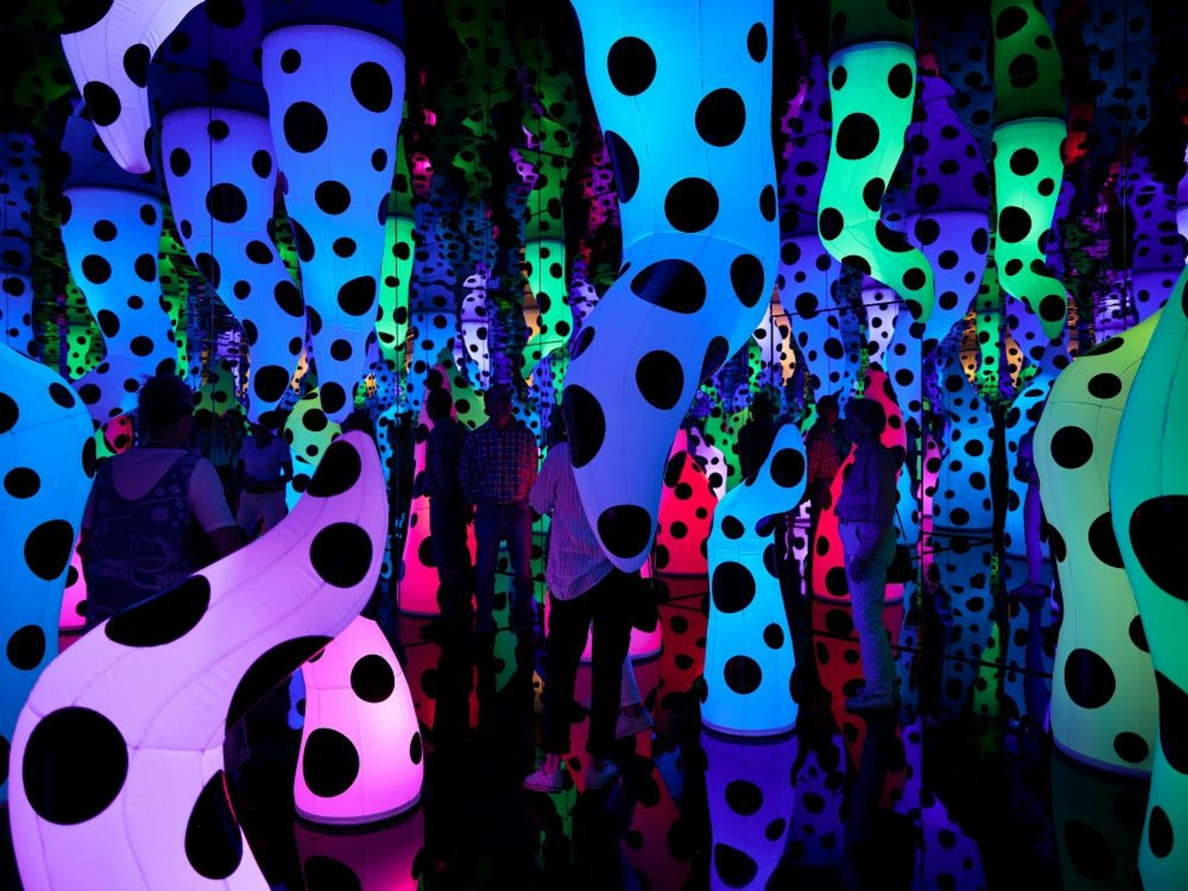 A vibrant, polka-dotted installation at Yayoi Kusama's exhibit in New York mirrors endless colorful shapes.