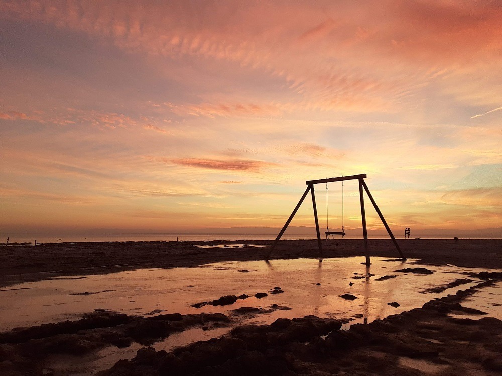 Beach with swing at sunset