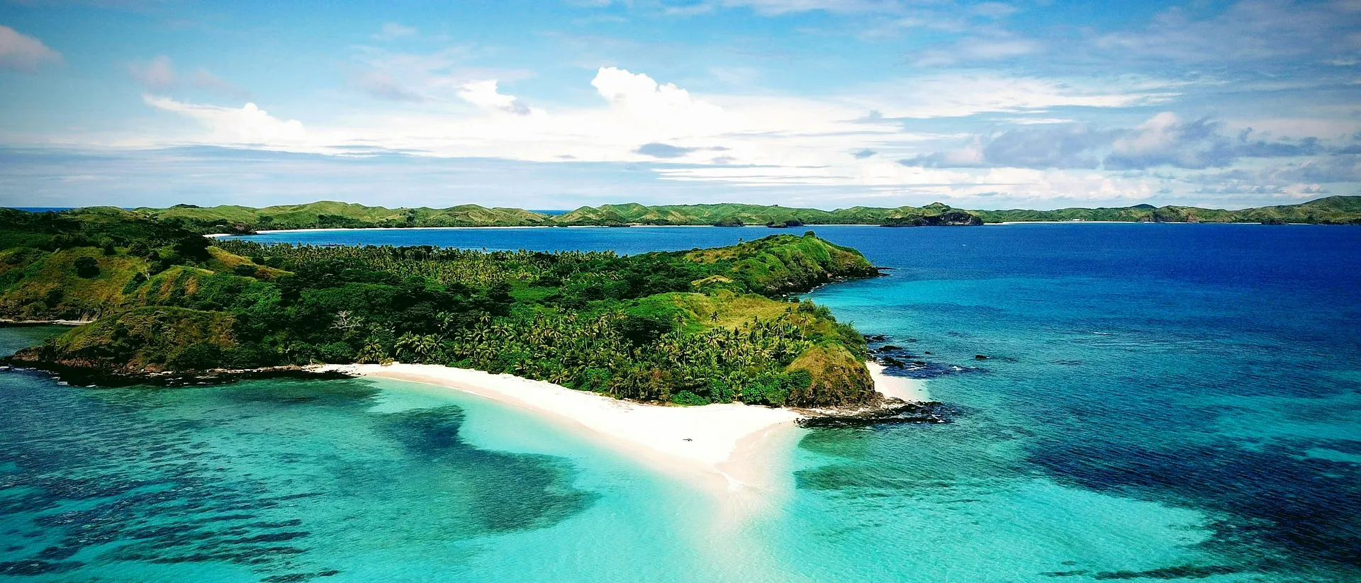 A scenic view with lush green hills and clear blue waters.