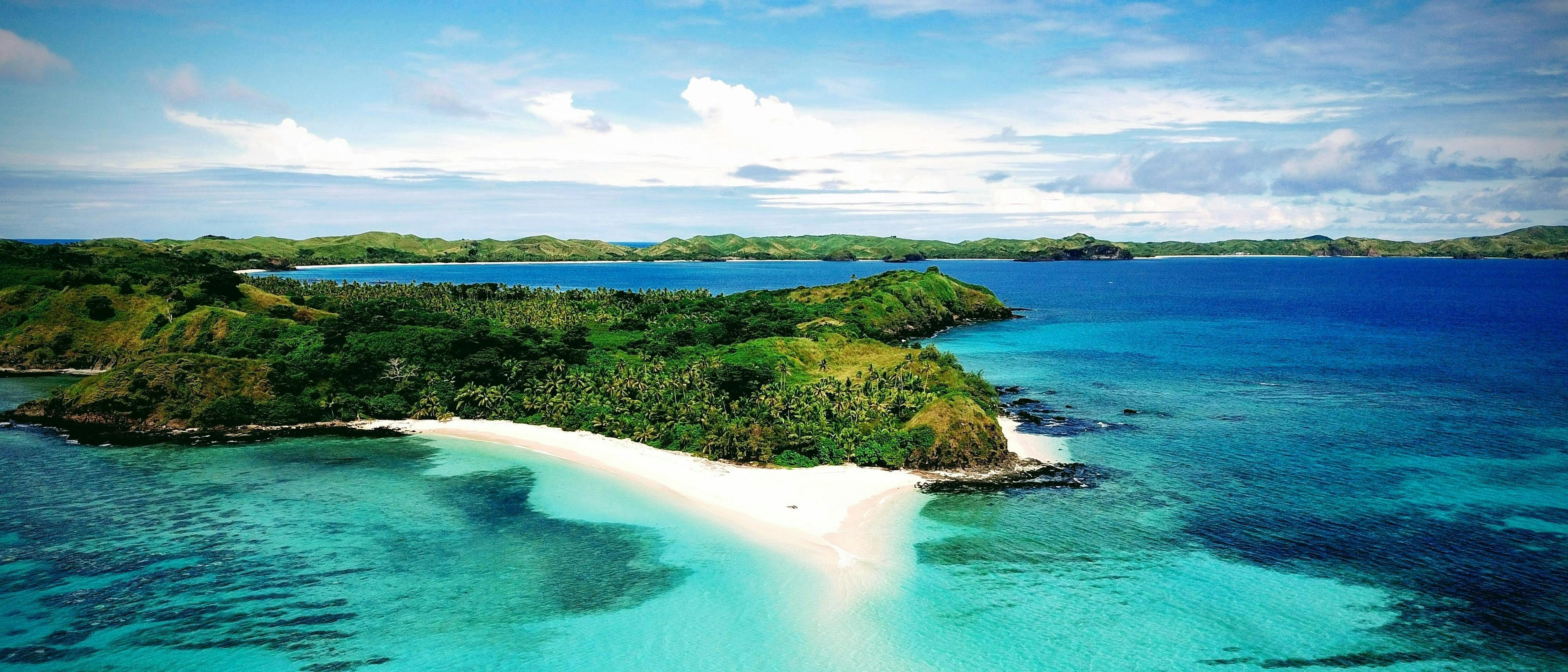 A scenic view with lush green hills and clear blue waters.