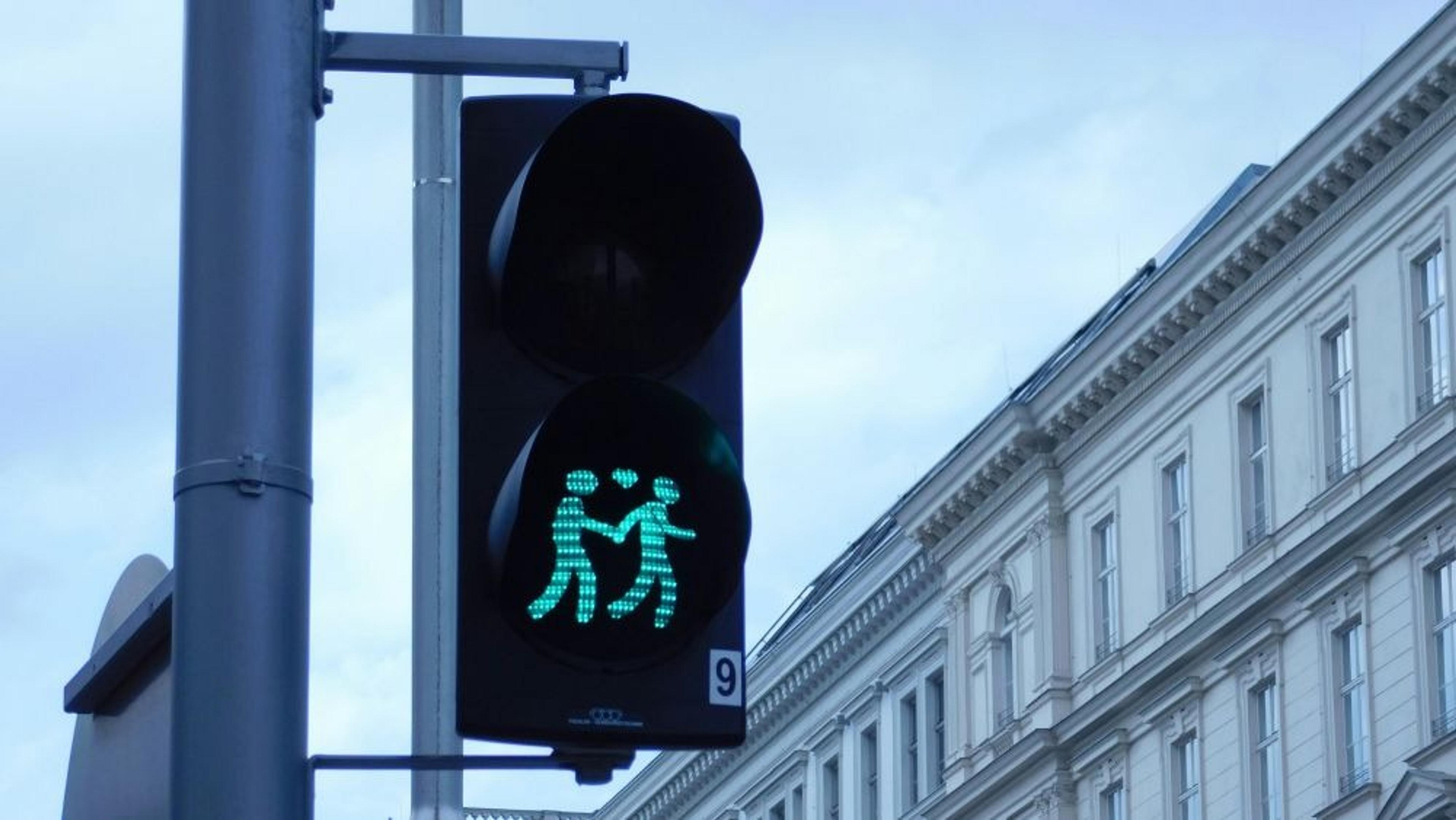 A unique traffic light in Vienna showcases a green pedestrian signal depicting two figures walking together.