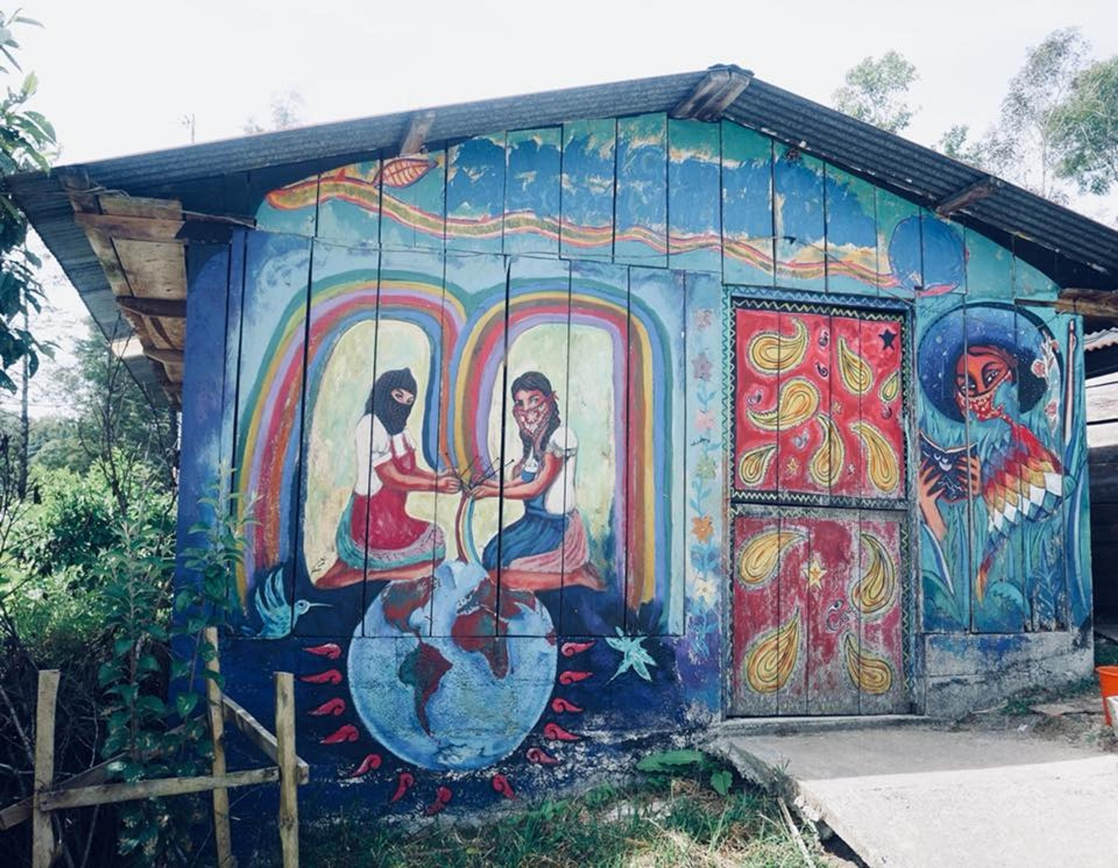 A vibrant mural covers a building in Chiapas, Mexico, depicting indigenous and revolutionary themes with colorful imagery and cultural symbolism.