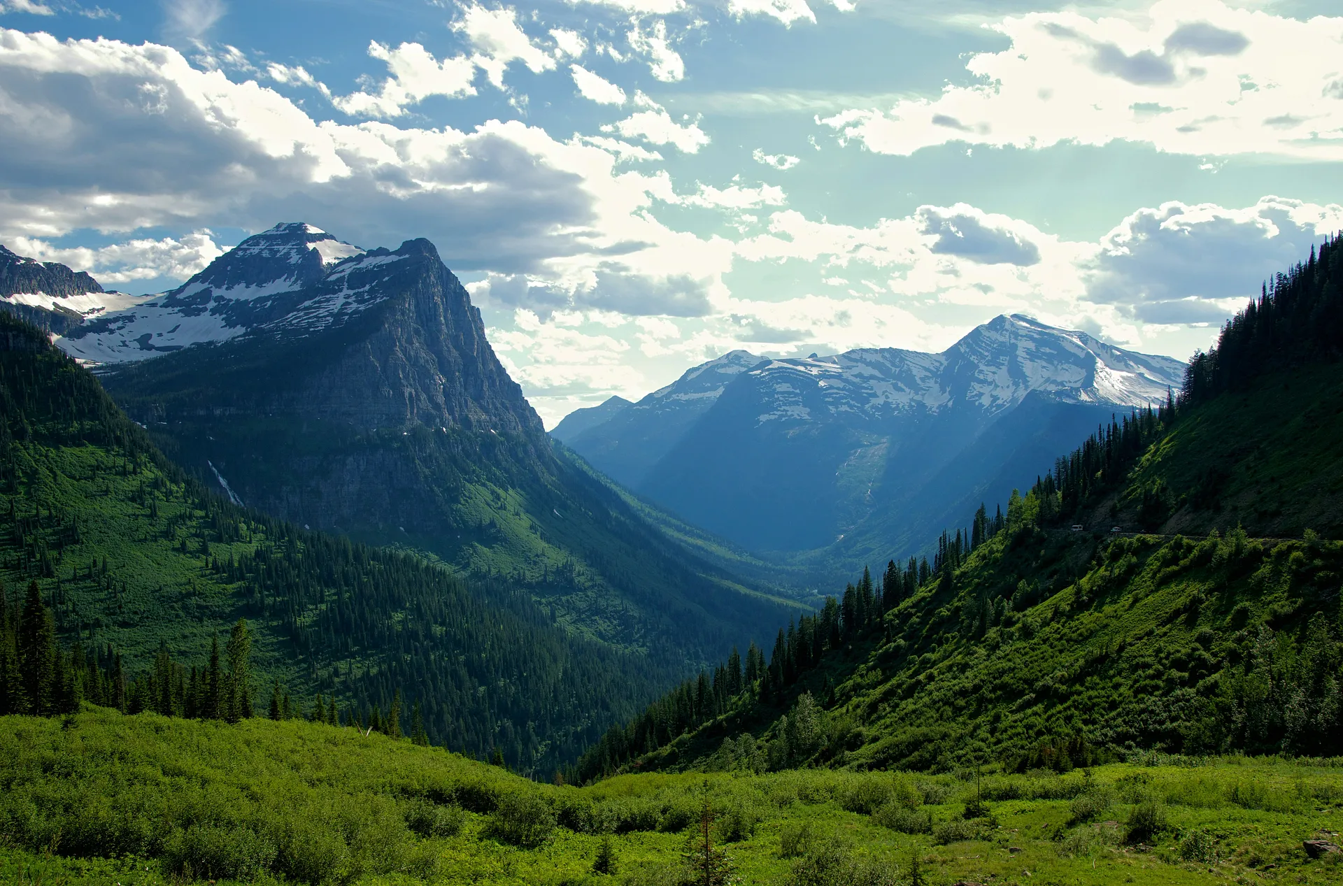 Lush green valleys and rugged, snow-capped peaks characterize Glacier National Park in Montana.