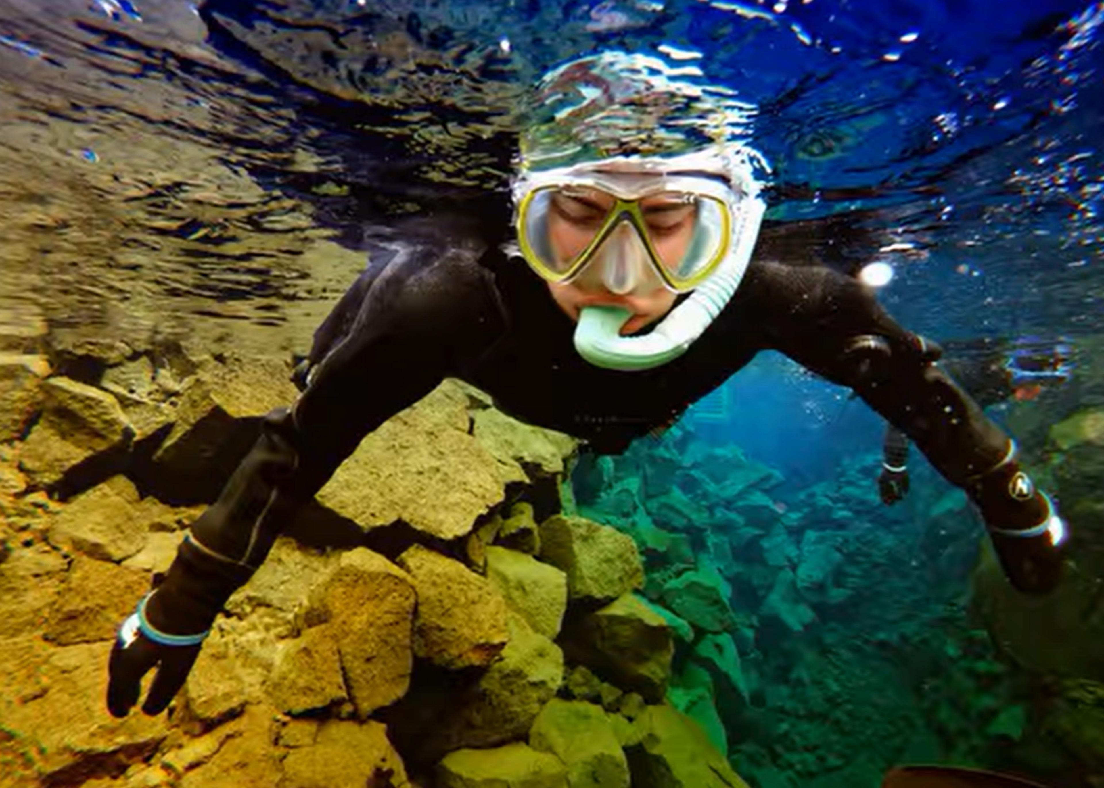 A snorkeler explores the crystal-clear waters of Silfra Fissure in Thingvellir National Park, Iceland.