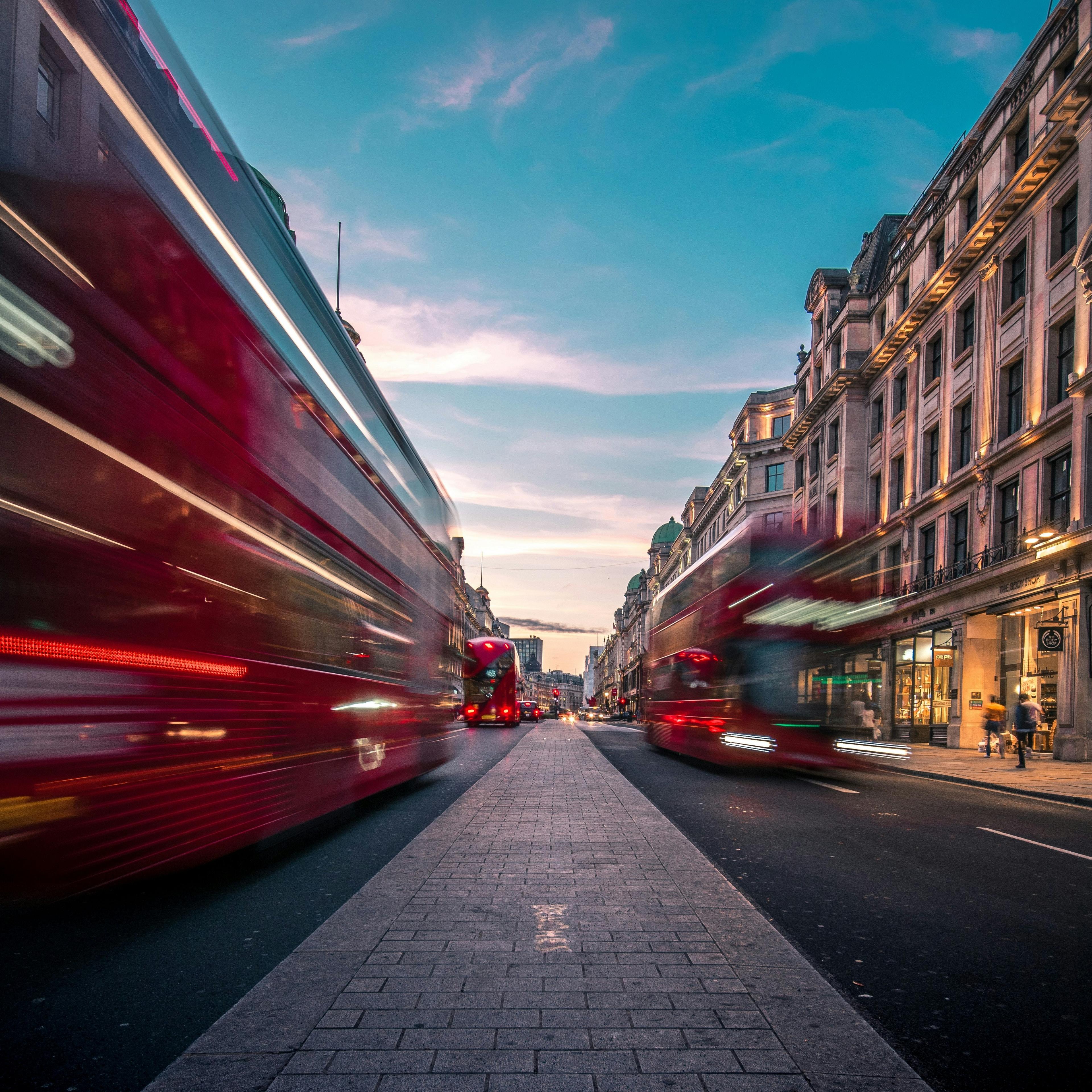A bustling evening scene with blurred red double-decker buses racing down Regent Street in London.