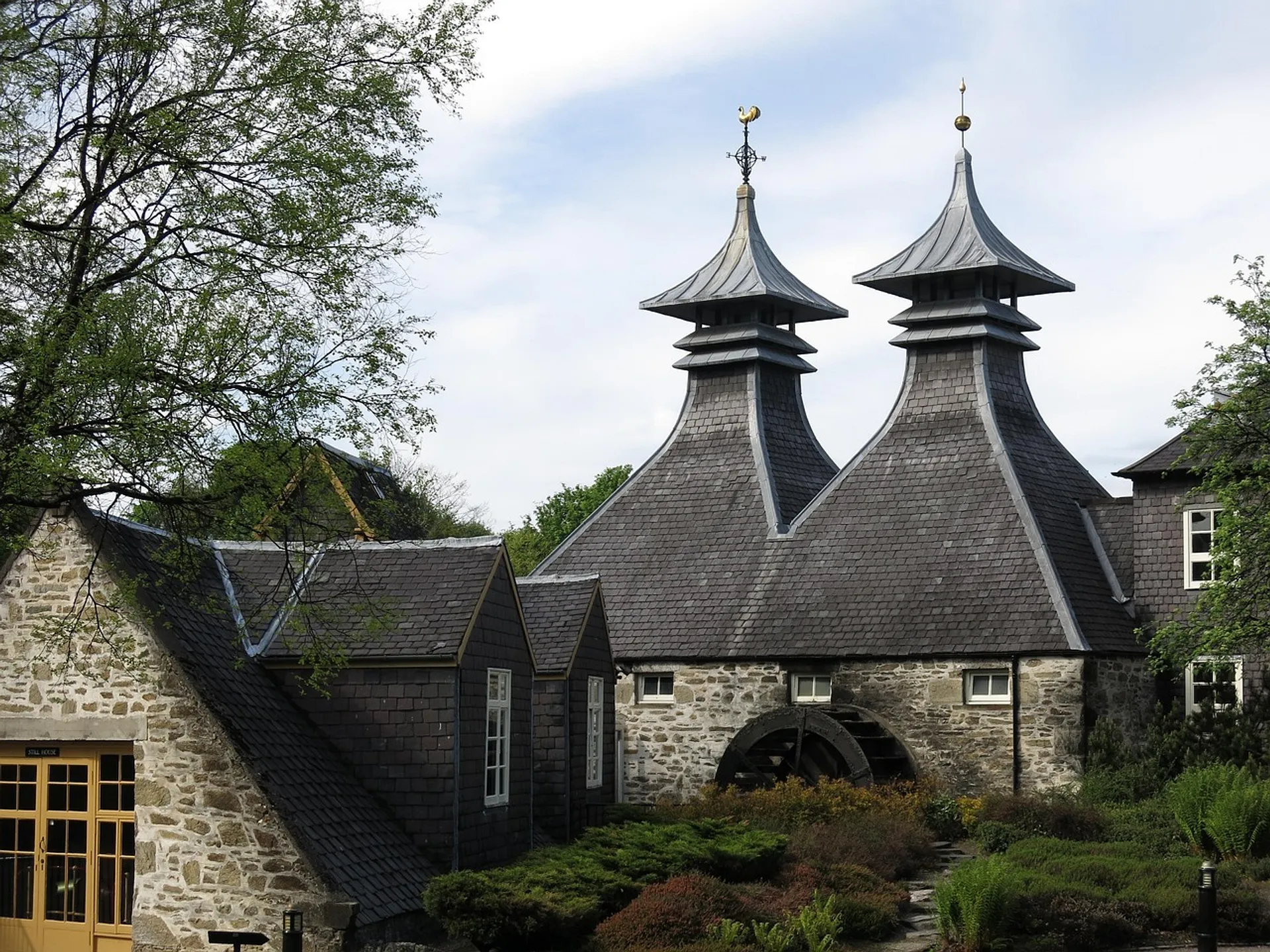 Traditional pagoda-like roofs adorn a historic distillery building surrounded by greenery in Speyside, Scotland.