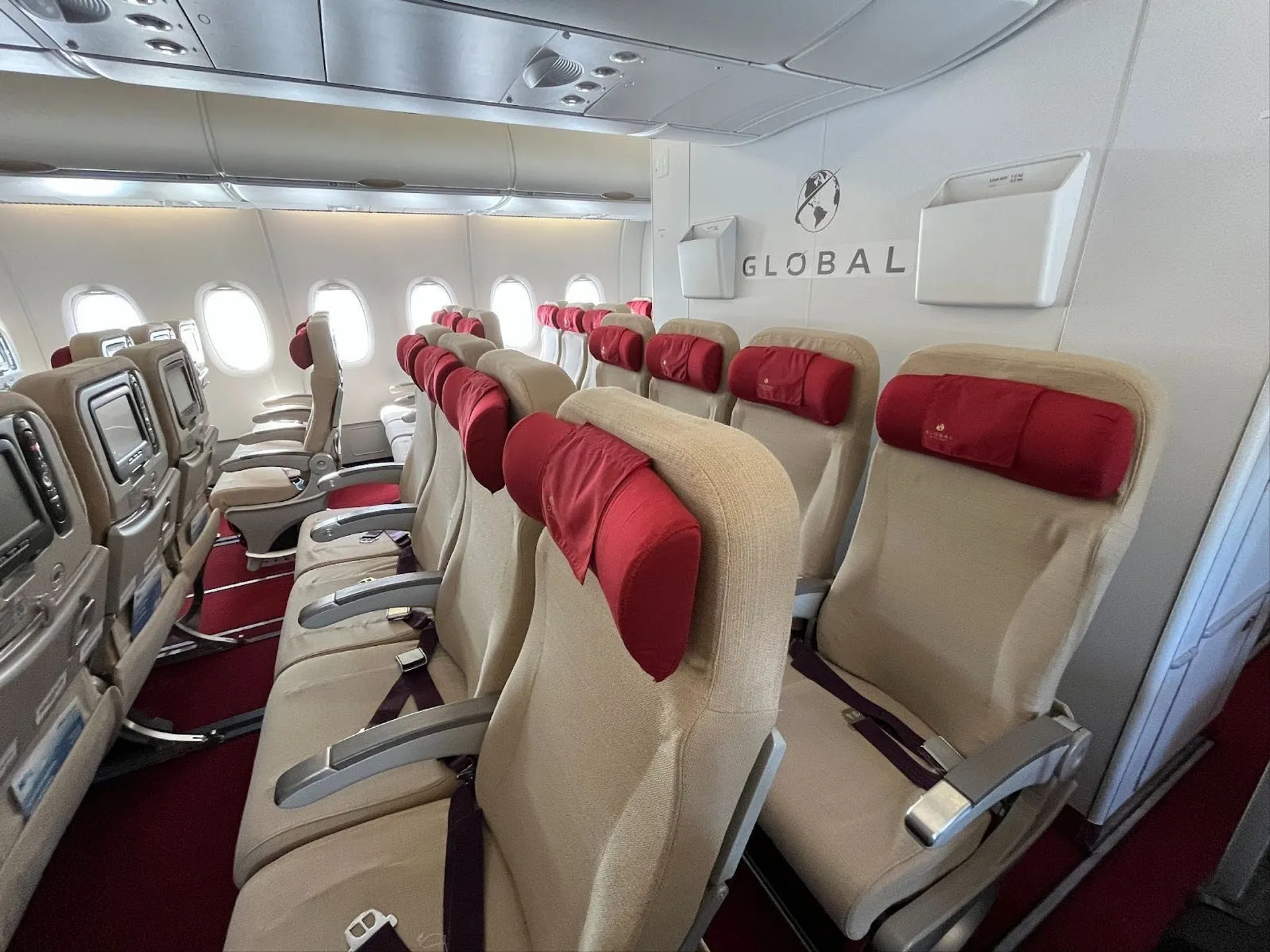 Red and beige Global Airlines seating, row of 4 in the centre of the aircraft