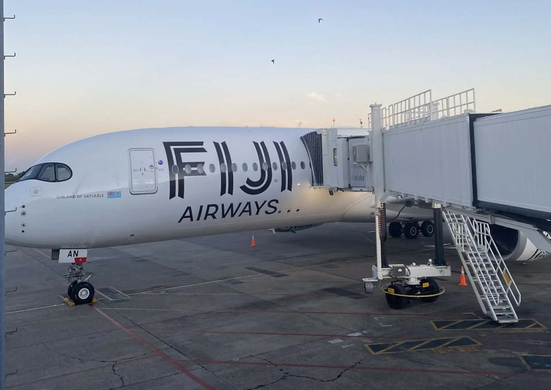 A Fiji Airways airplane is parked at a jet bridge, likely at Nadi International Airport.
