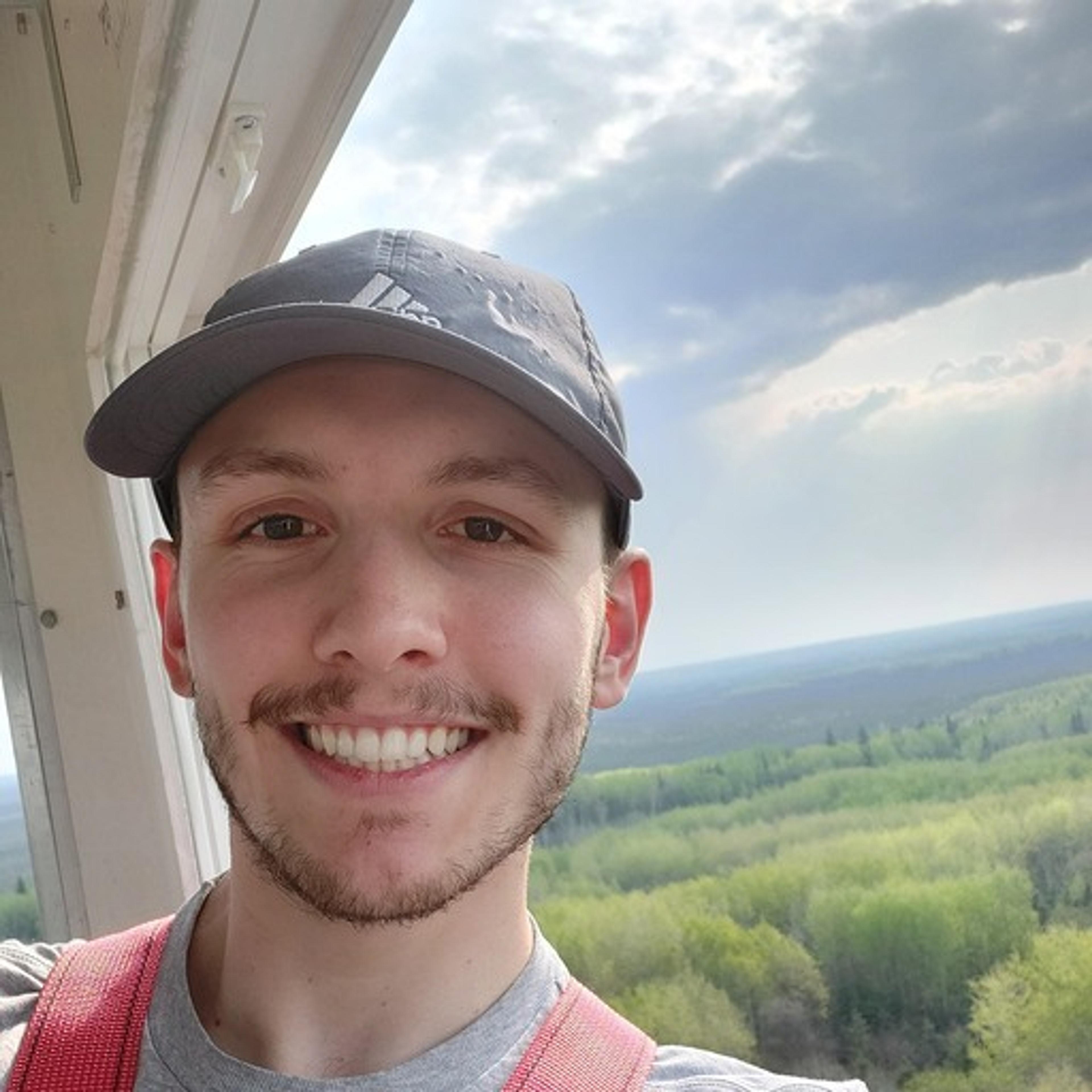 A person takes a selfie amidst the mountainous landscapes and dense forests of Kananaskis Country in Alberta.