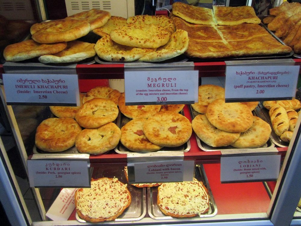 A display of various types of khachapuri and other Georgian pastries can be seen in a bakery in Georgia.