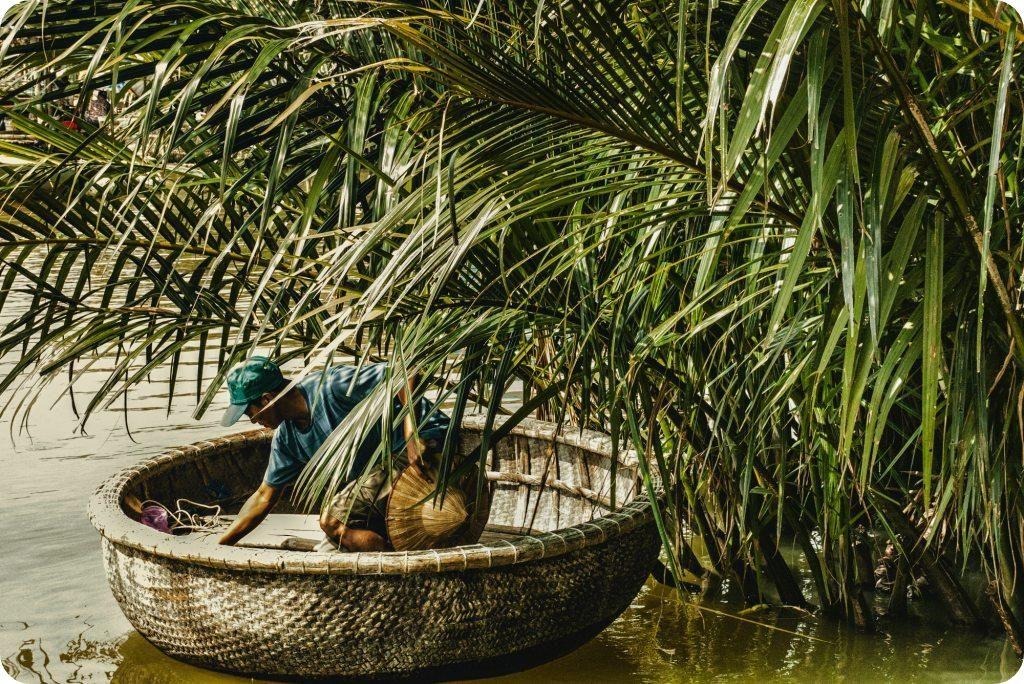 Man in basket boat surrounded by plants