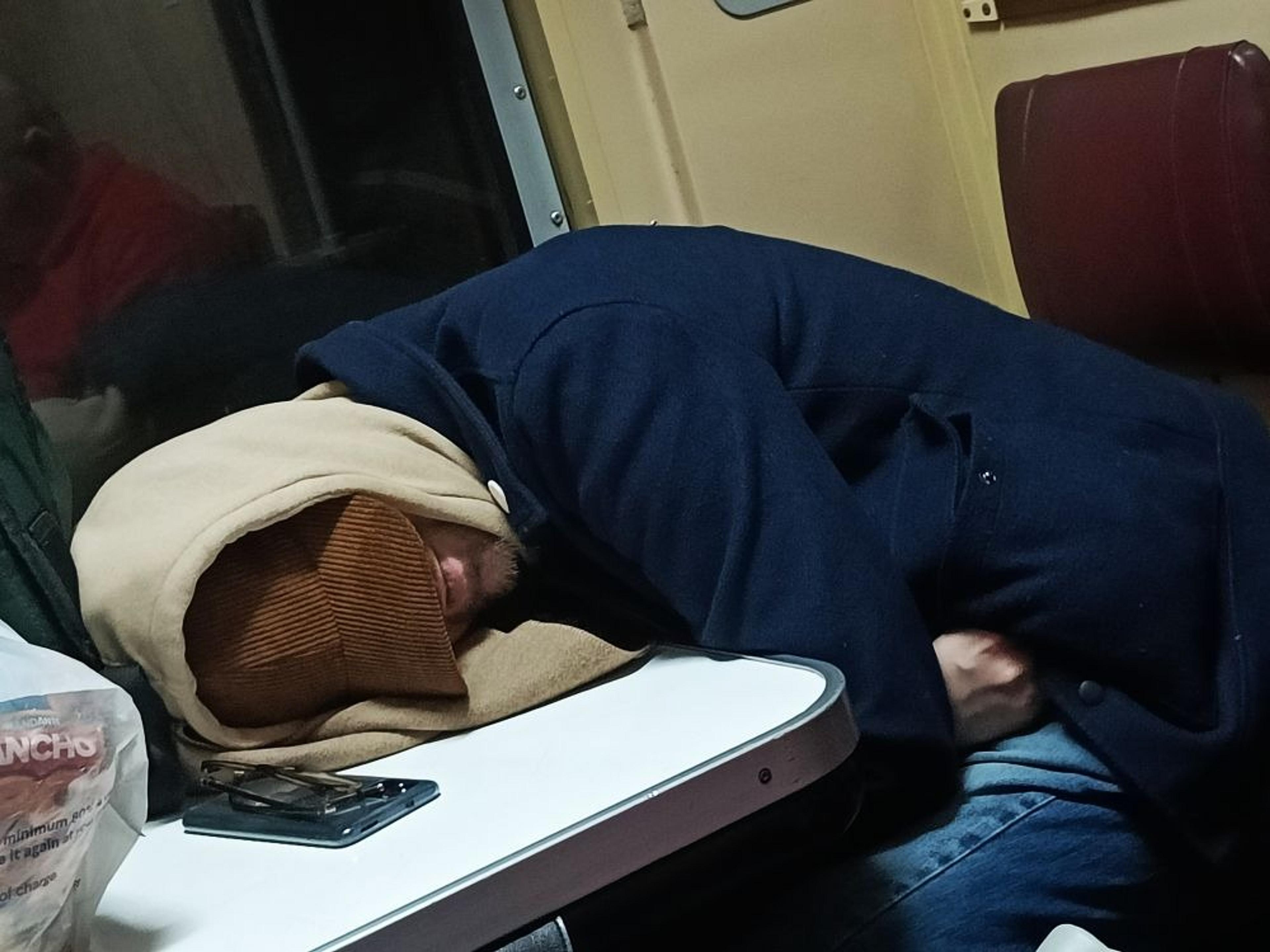 A person is sleeping on a table inside a train compartment.
