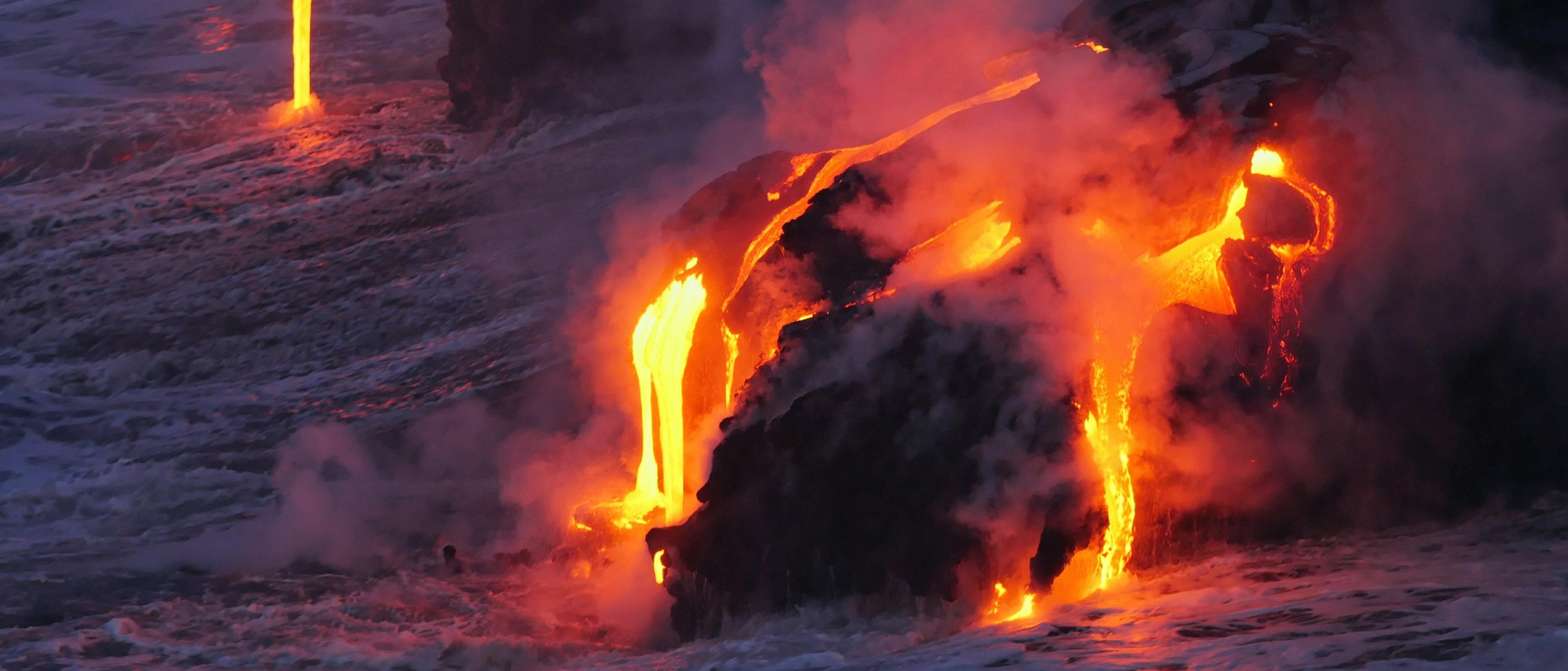 Molten lava dramatically cascades into the ocean at Kilauea Volcano, Hawaii.
