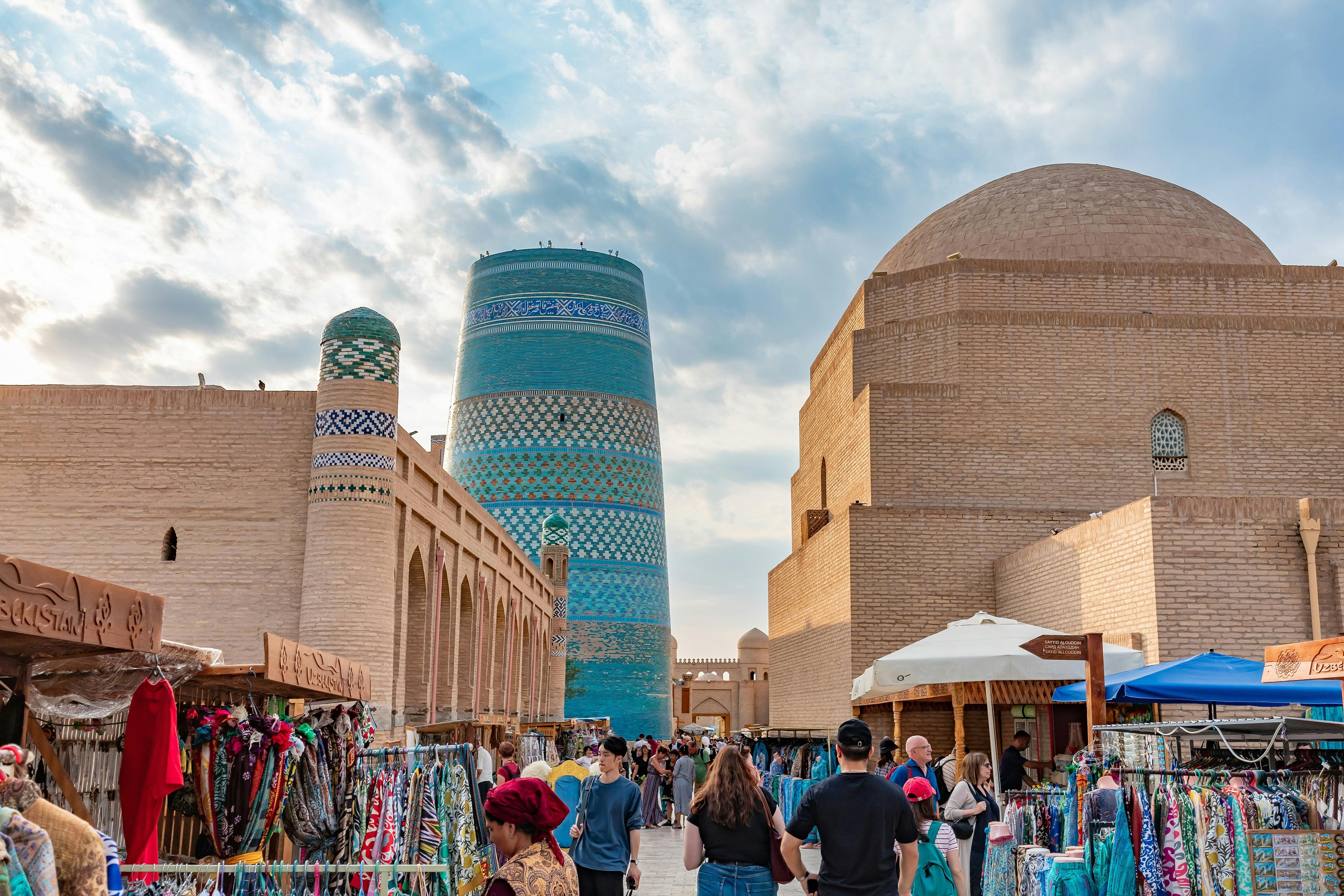 A bustling market scene unfolds in front of the iconic Kalta Minor Minaret in Khiva, Uzbekistan.