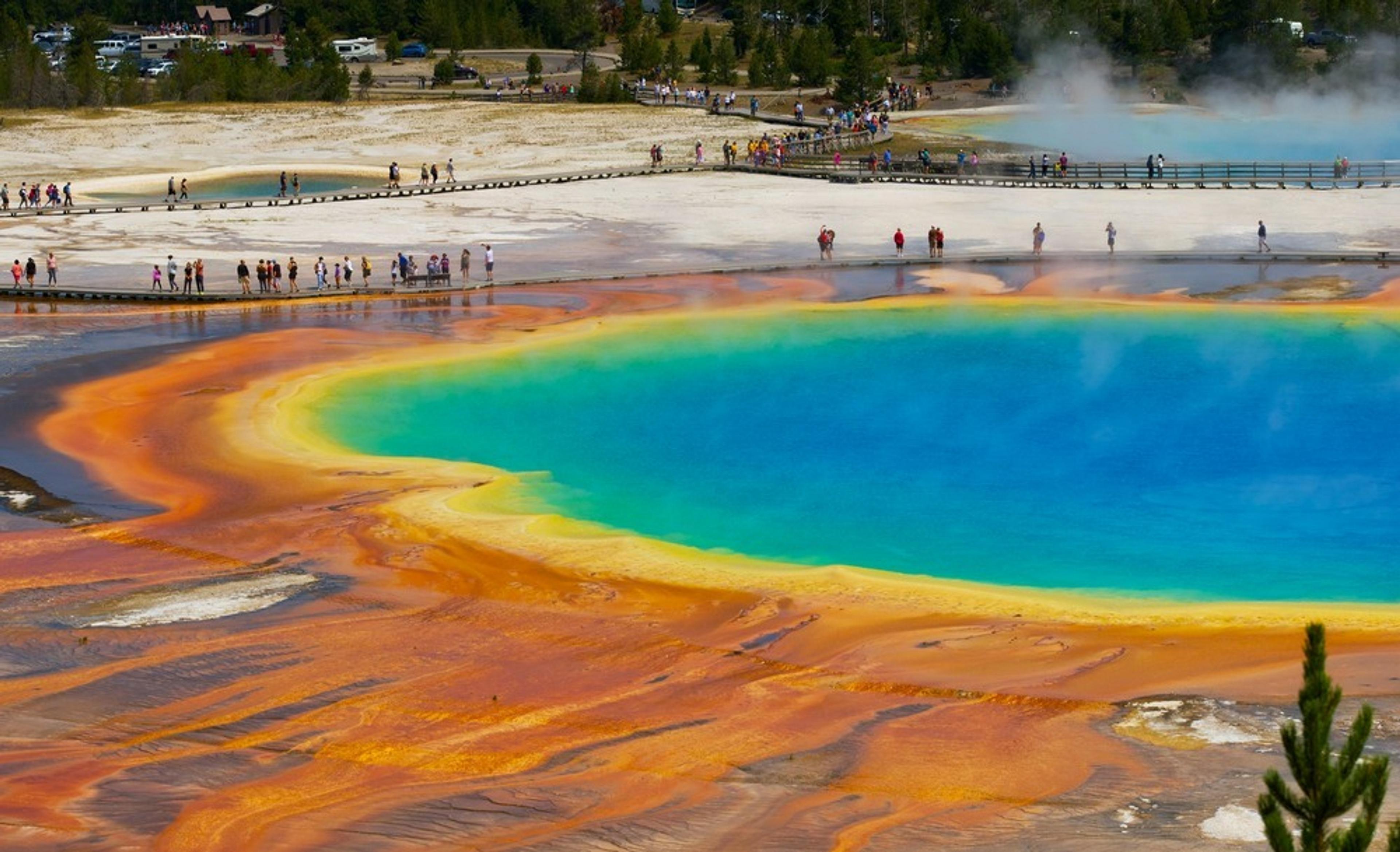 Vibrant colors surround the Grand Prismatic Spring in Yellowstone National Park, drawing numerous visitors along the boardwalks.