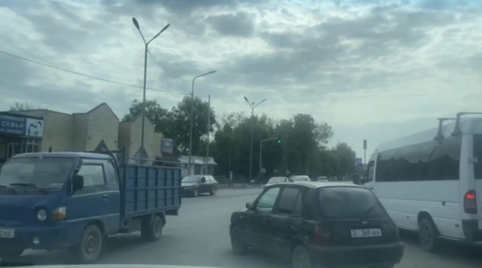 A busy intersection in Bishkek, Kyrgyzstan, with various vehicles and cloudy skies.
