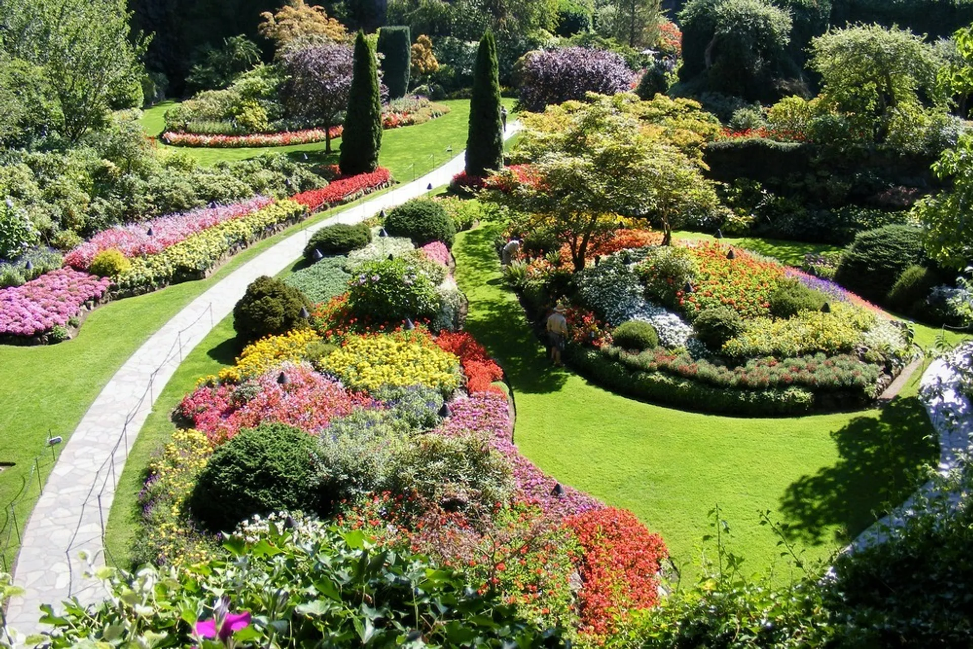 A vibrant array of meticulously arranged flowers and lush greenery adorns the Sunken Garden in Butchart Gardens, Canada.