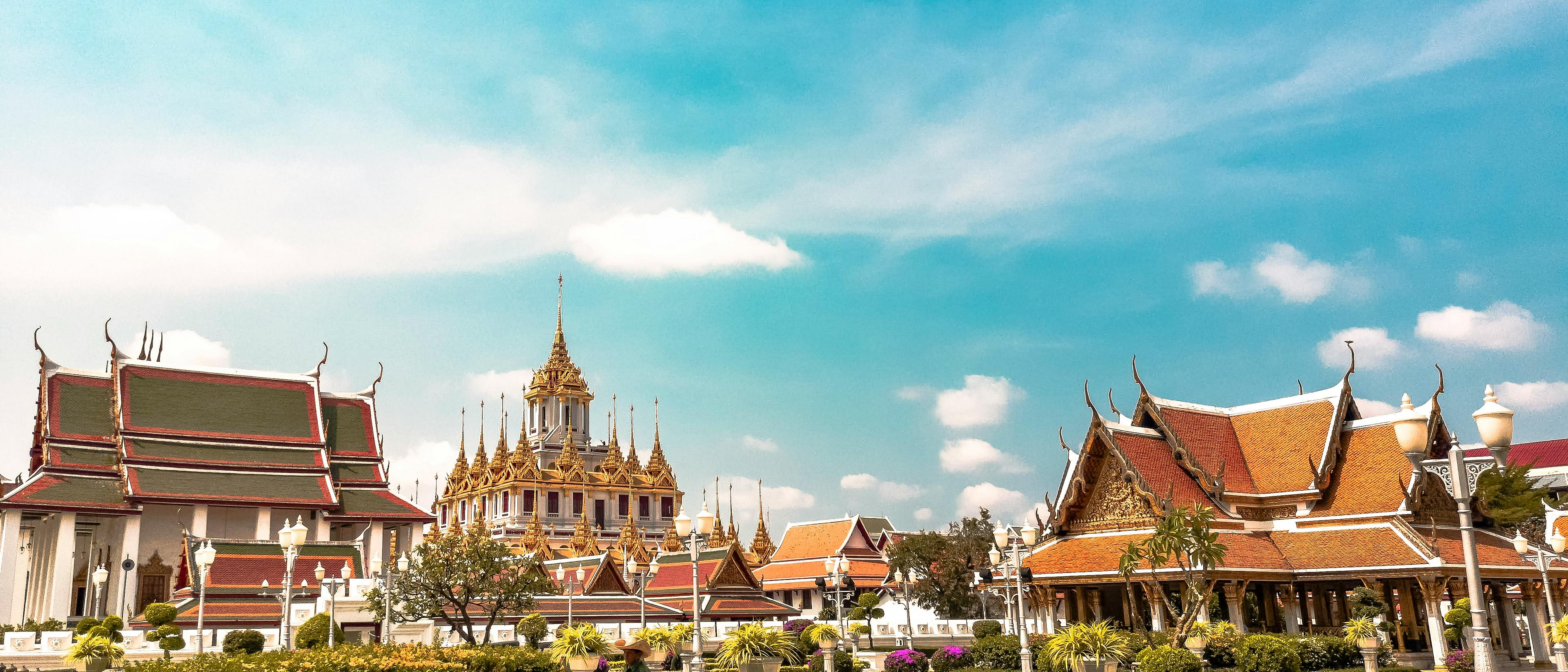 Ornate Thai architecture with intricate rooftops and spires fills the scene in Bangkok.