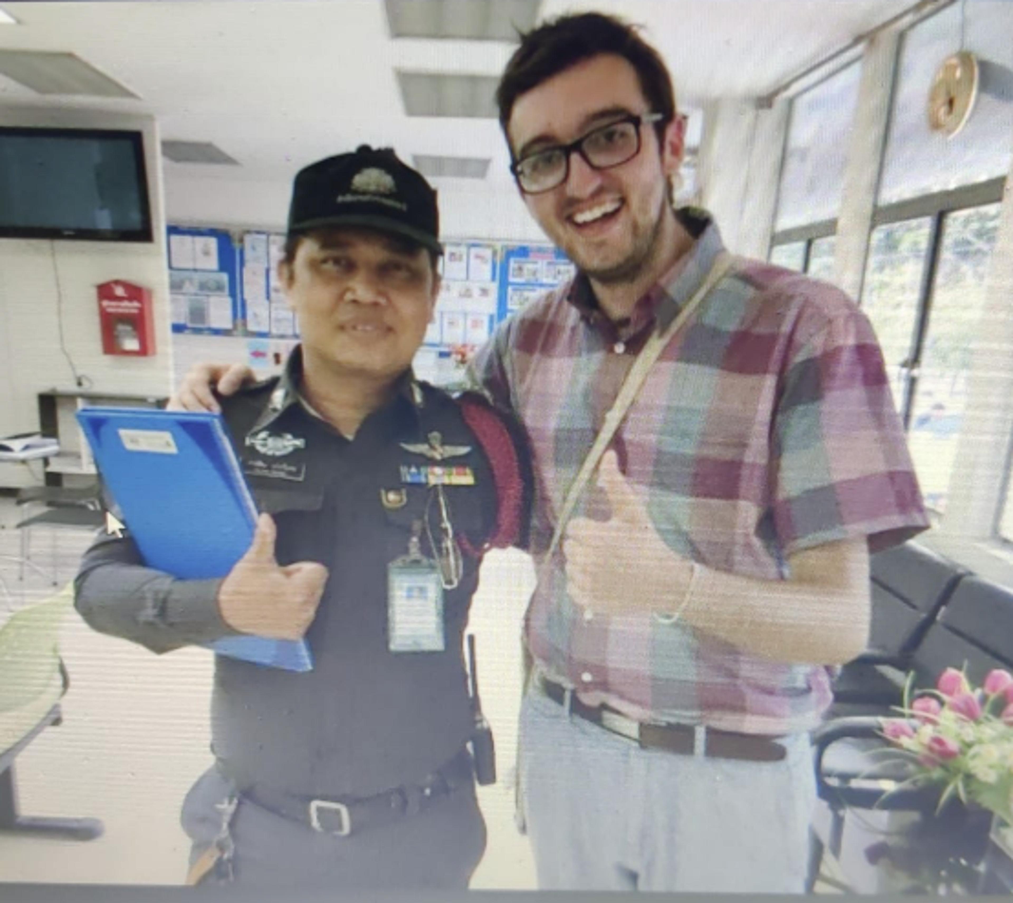 A person poses with a security officer inside a modern office or facility, possibly in an airport or governmental building.
