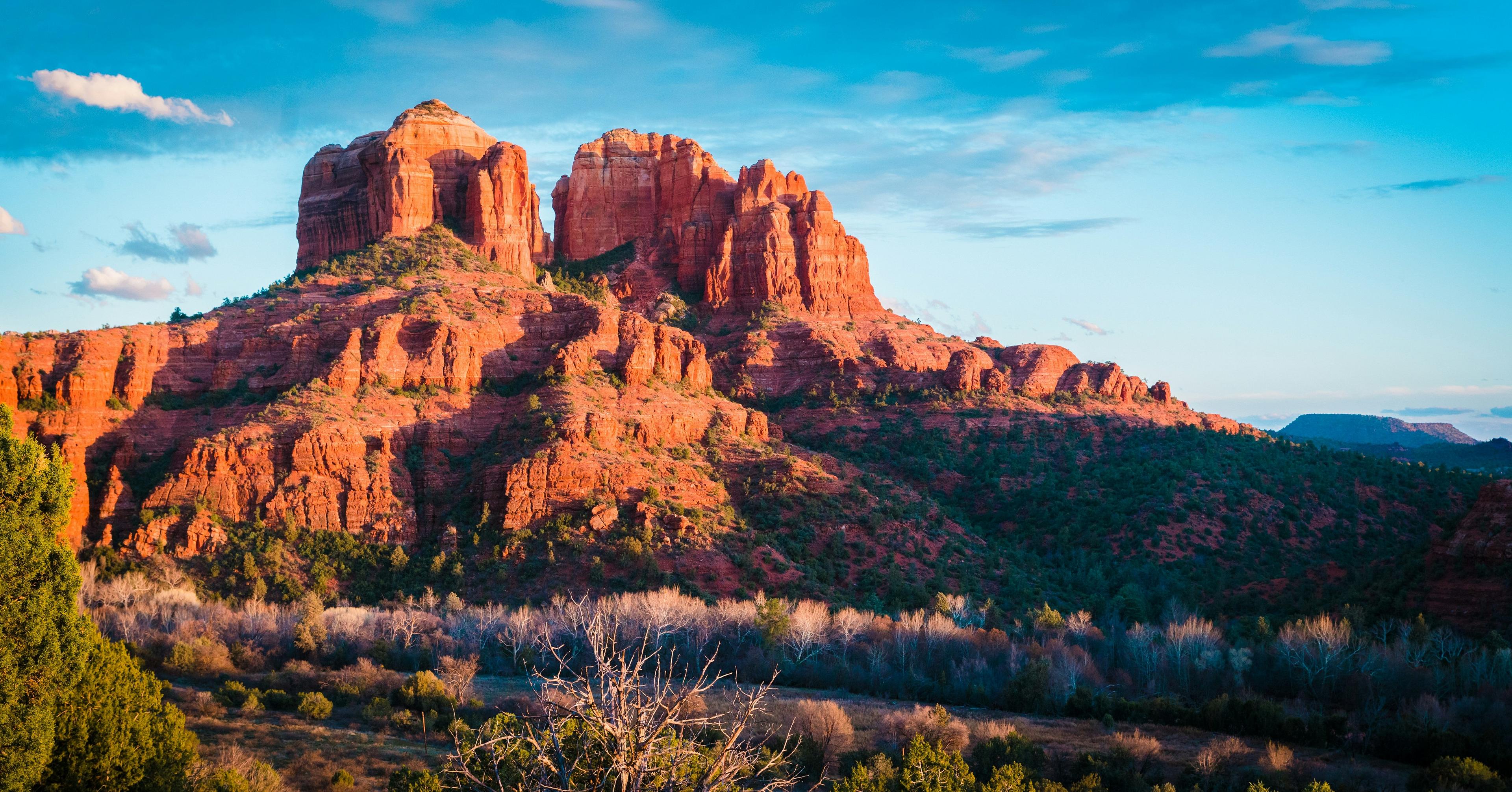 Cathedral Rock in Sedona, Arizona stands majestically with its iconic red sandstone formations under a blue sky.