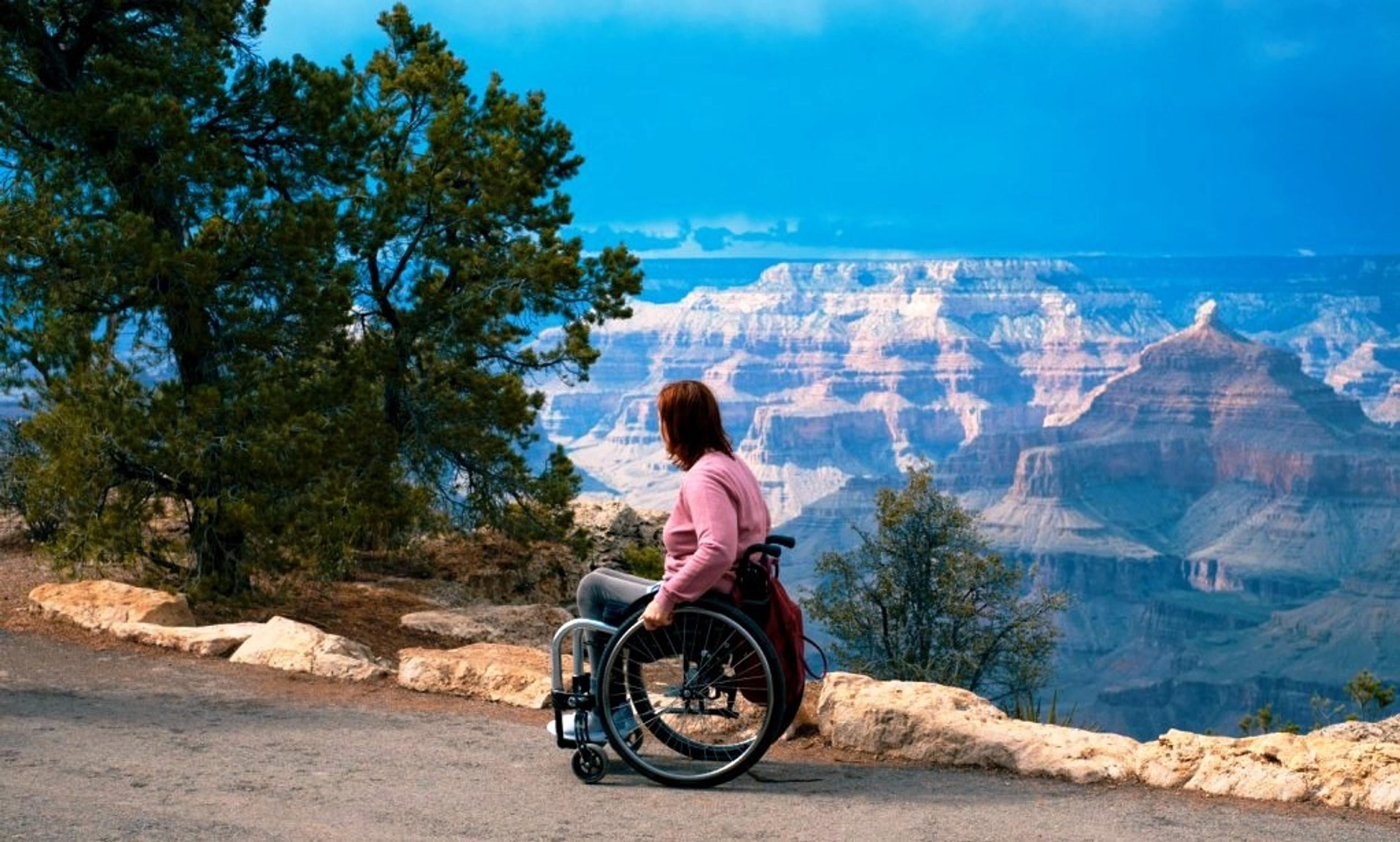 A wheelchair user on a road overlooking epic mountainous scenery