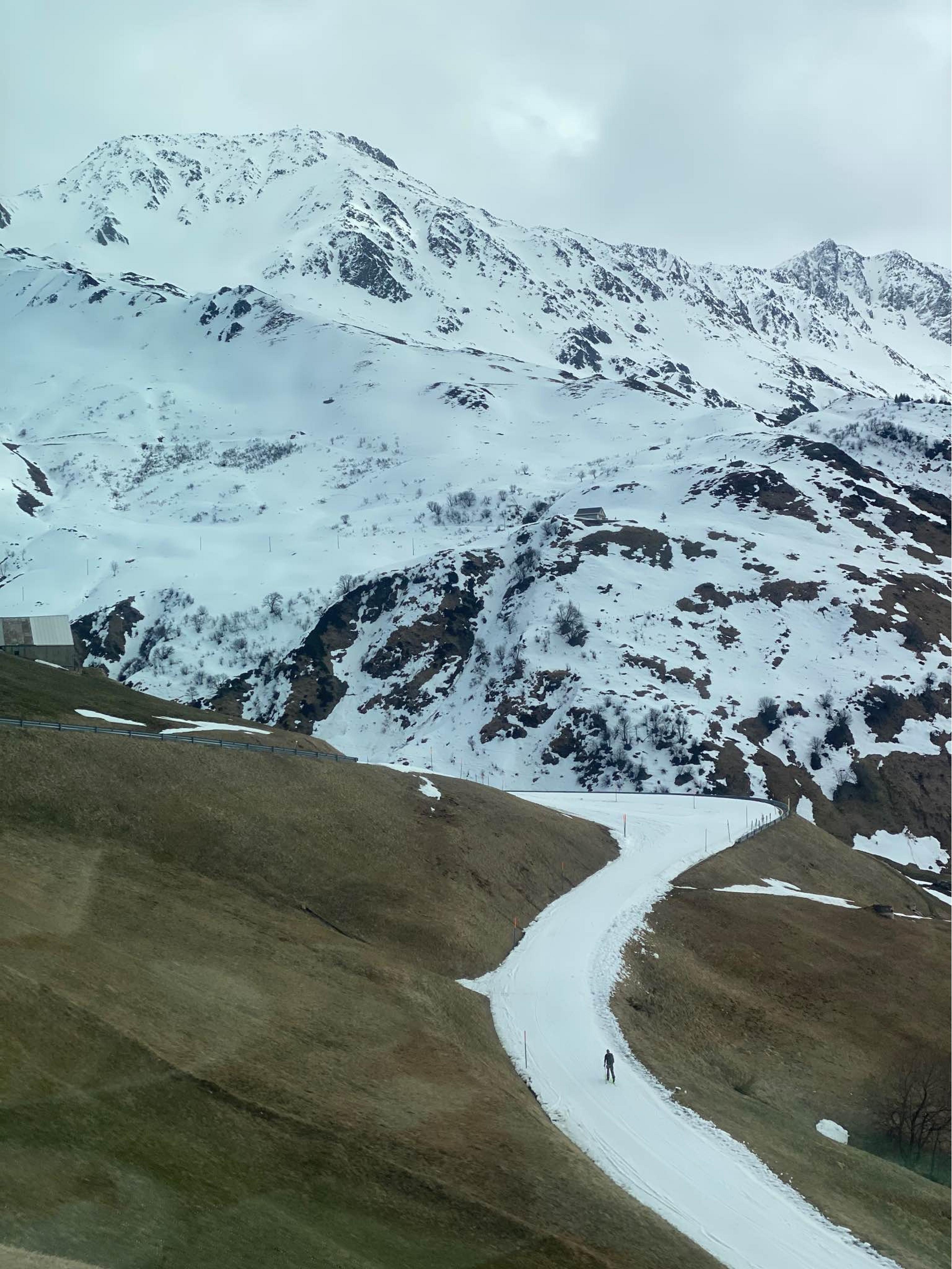 A lone skier navigates a snowy trail amid the mountainous landscape of the Swiss Alps.
