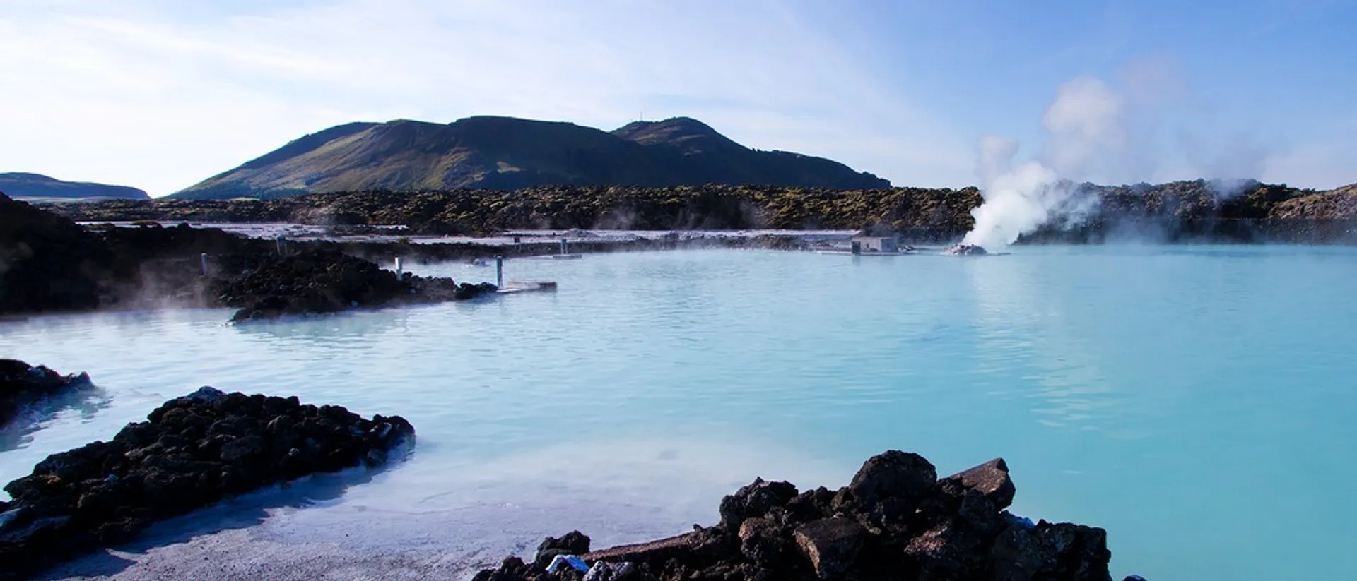 A serene view of the geothermal waters at the Blue Lagoon in Iceland, surrounded by rugged volcanic landscapes.