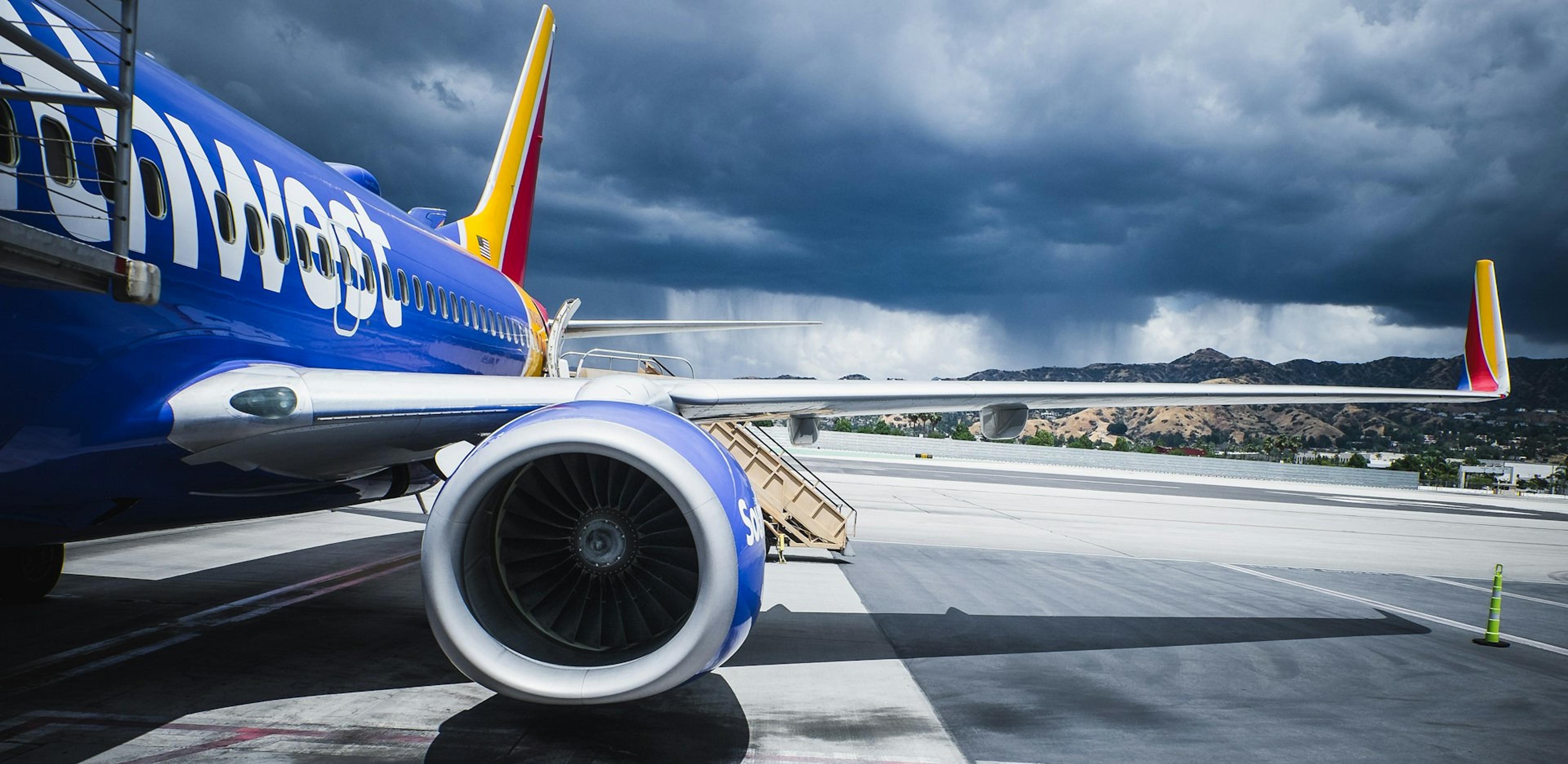 A Southwest Airlines plane is parked on the tarmac at Burbank Airport, with dark storm clouds gathering above.