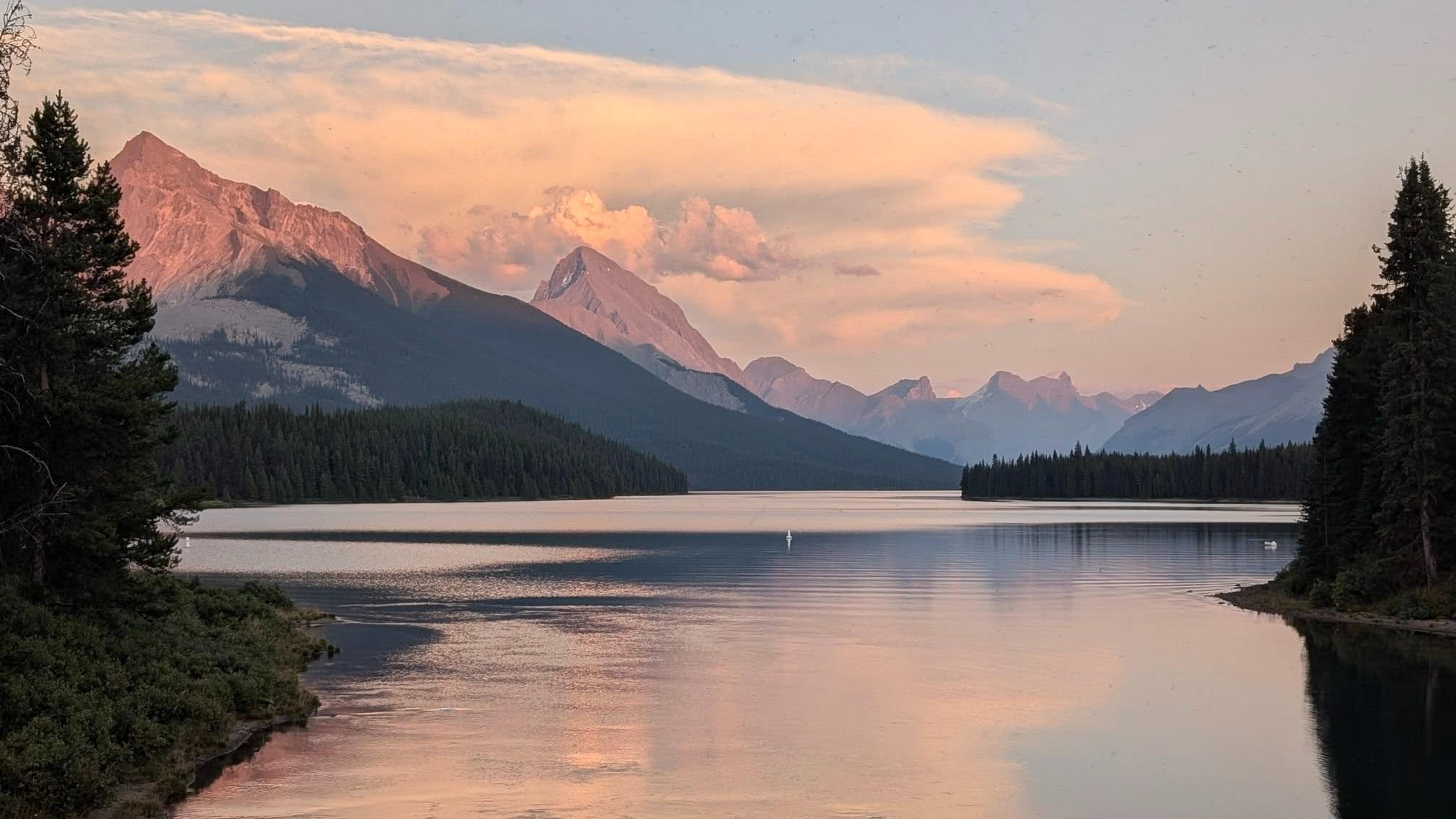 Serene landscape of Maligne Lake in Jasper National Park, Canada, with majestic mountains at sunset.