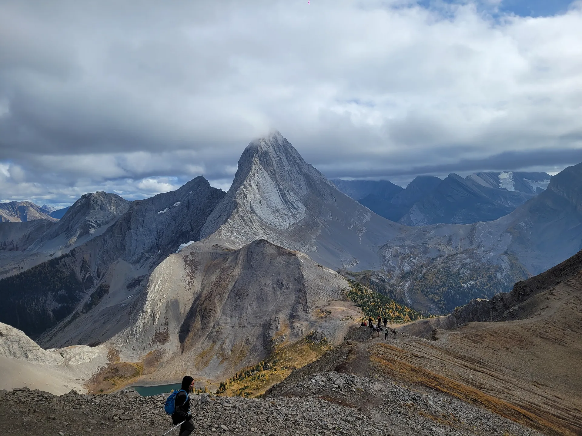 A hiker walks along a ridge in front of the towering peaks of The Fortress in Kananaskis Country, Alberta.