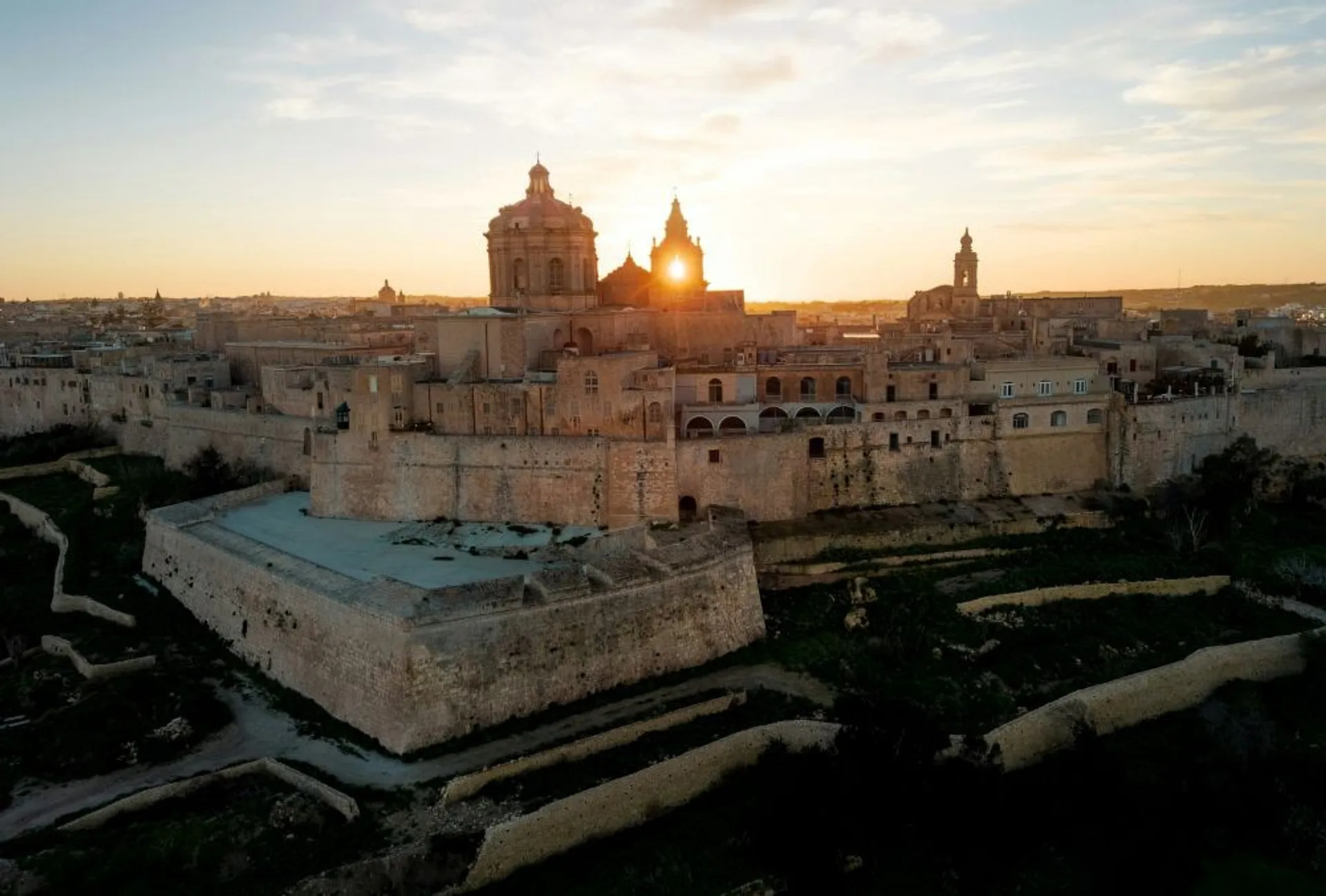 Mdina, the ancient fortified city in Malta, is bathed in golden sunlight at sunset.