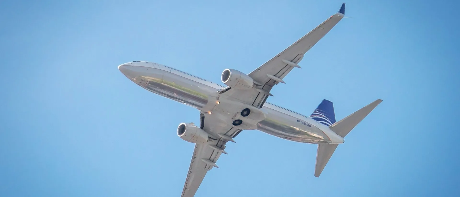 A commercial airplane in flight, captured against a clear blue sky.