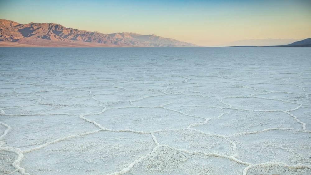 Expansive salt flats stretch across Badwater Basin in Death Valley, California, with distant mountains skirting the horizon.
