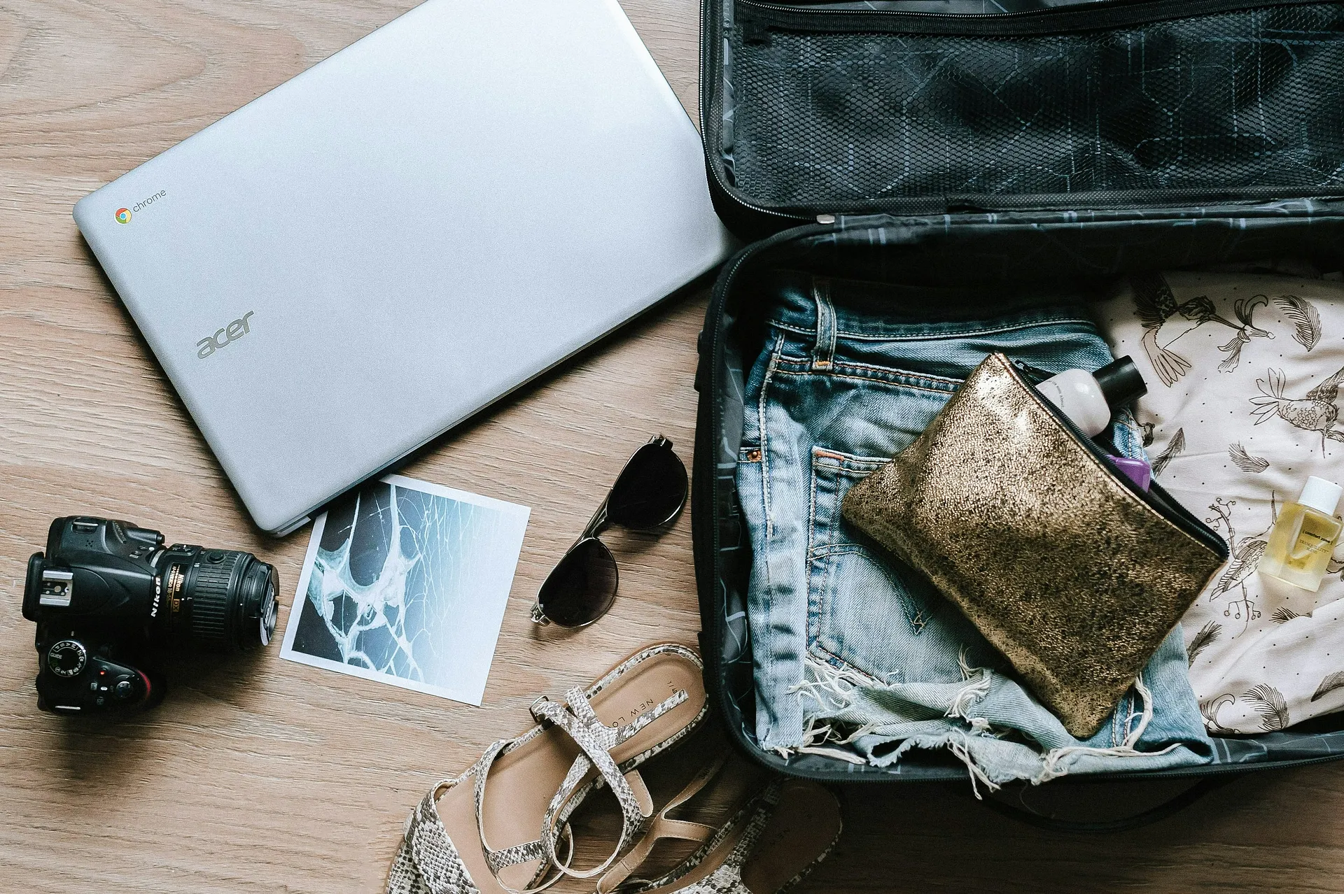 Open suitcase with laptop, camera and sunglasses