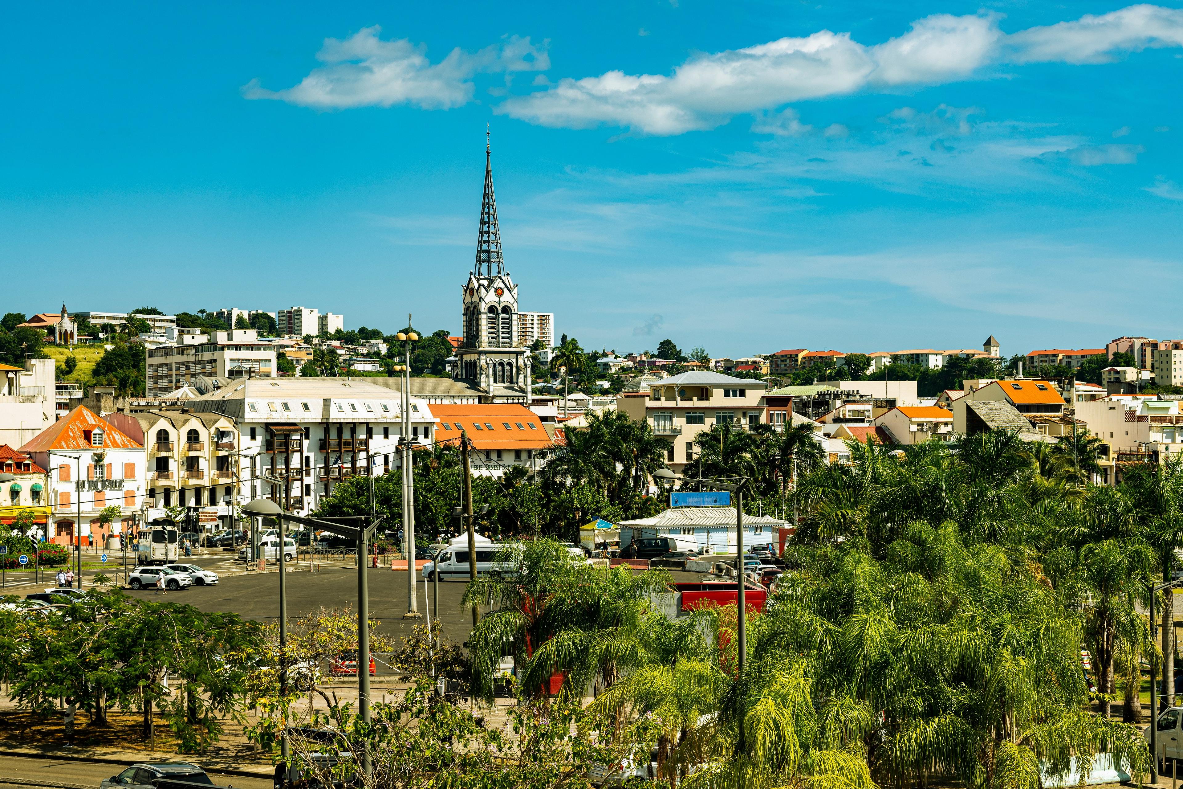 A sunny day in Fort-de-France, Martinique, featuring the iconic spire of Saint Louis Cathedral rising above the cityscape.