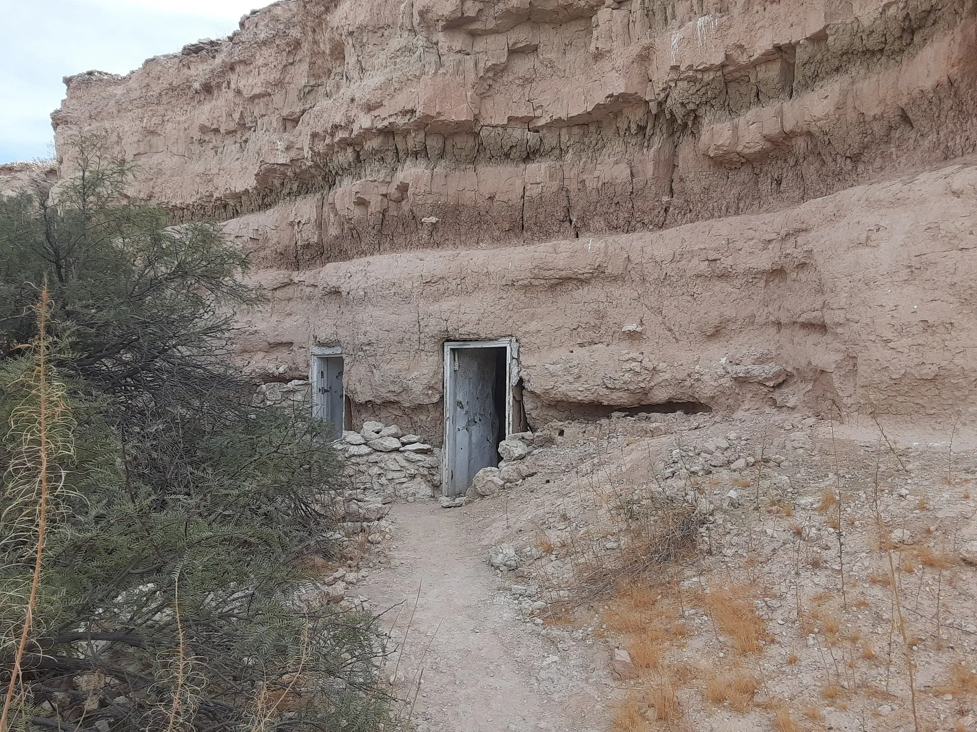 Two weathered wooden doors are nestled into a rugged cliff face
