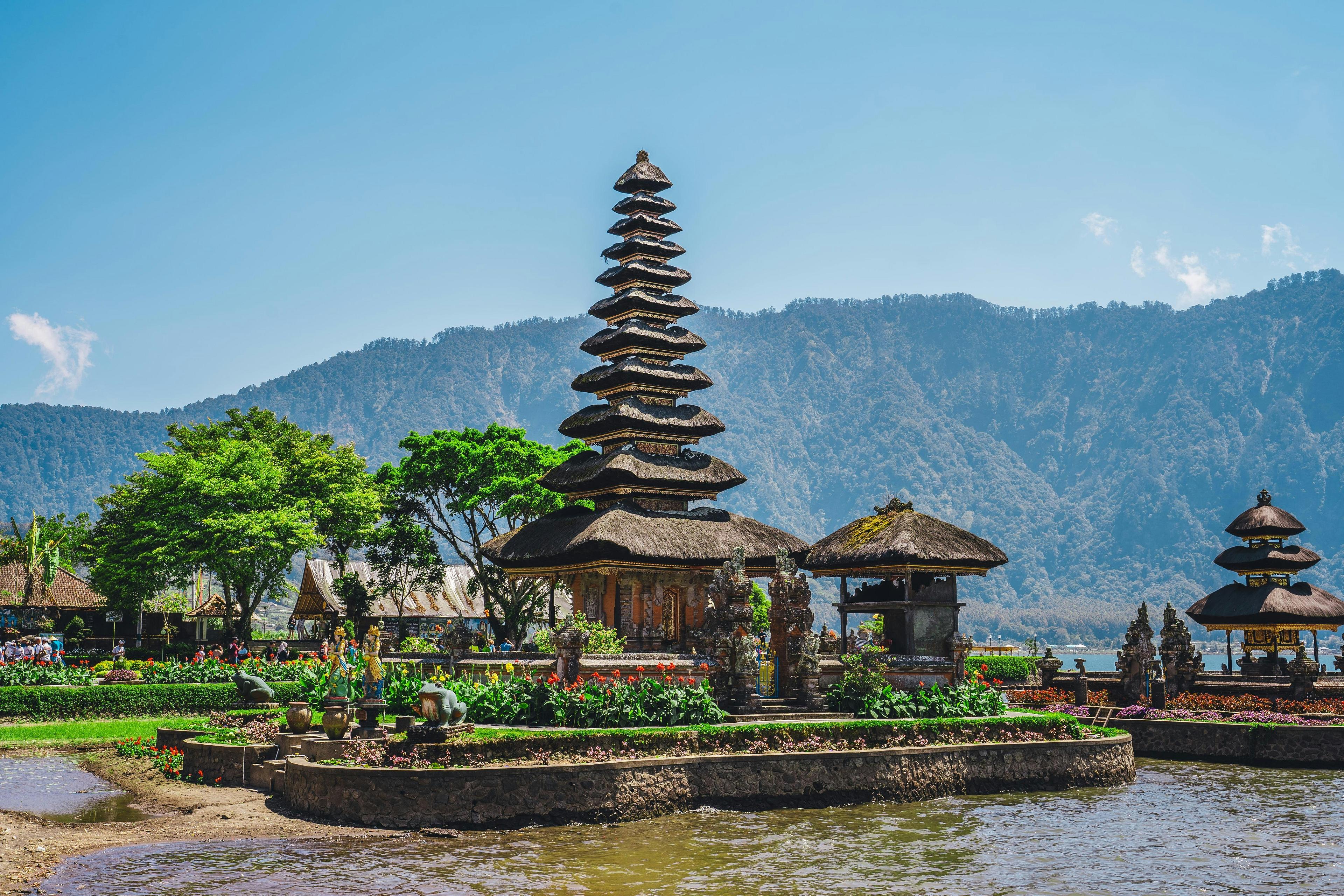 A picturesque water temple, stands against a backdrop of mountains in Bali, Indonesia.