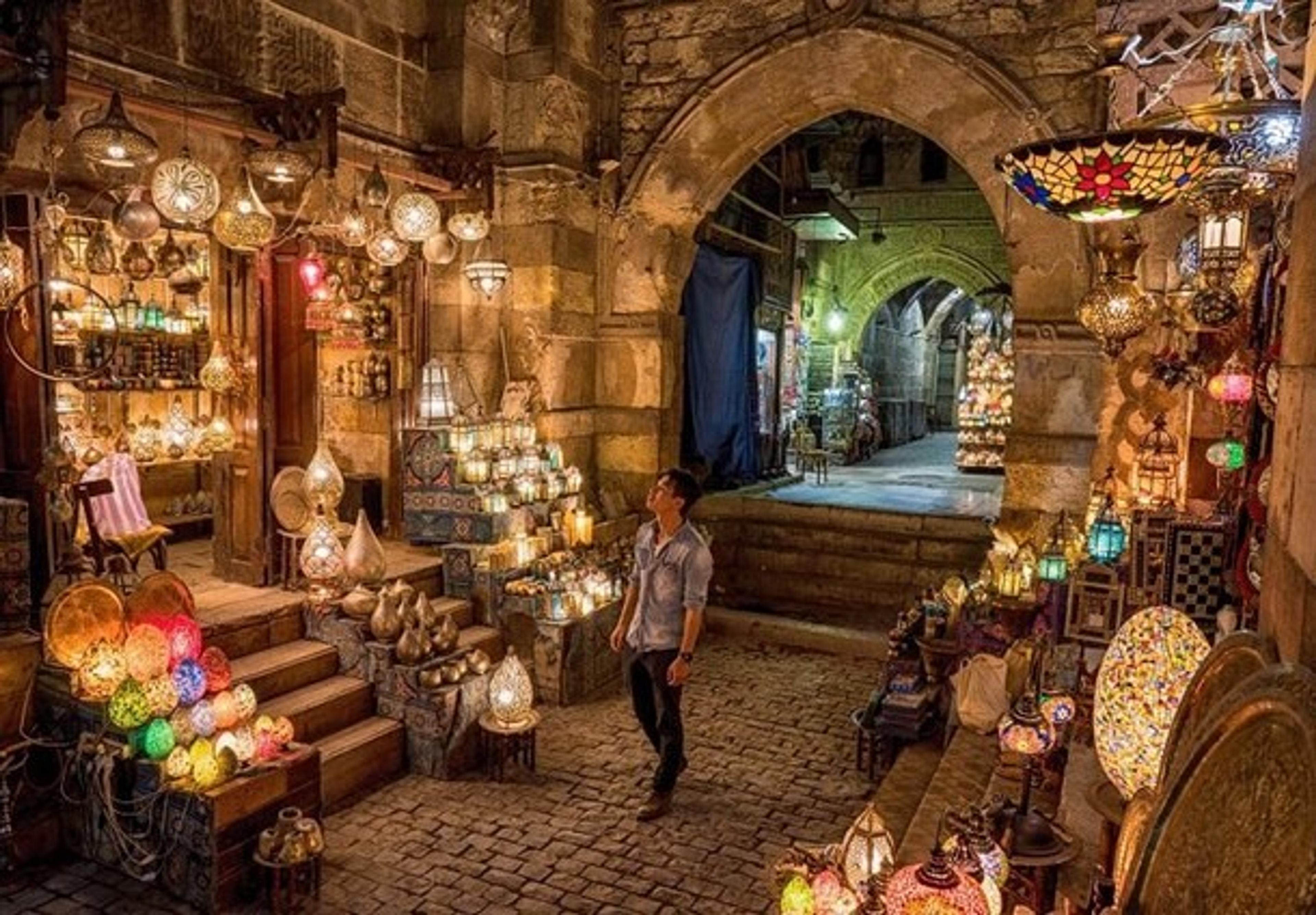 A man stands in cavernous market surrounded by lanterns