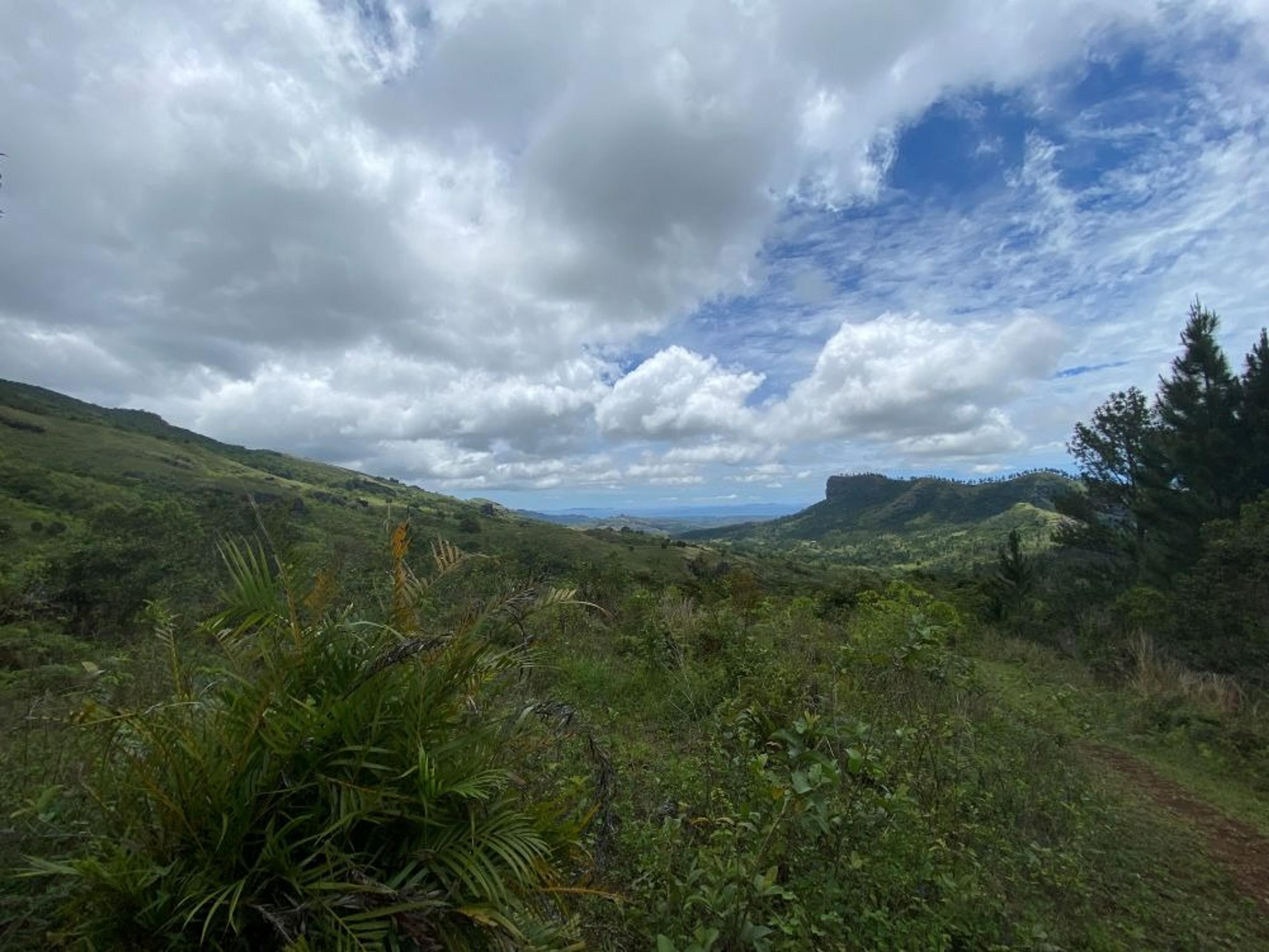 A lush, green landscape stretches under a cloudy sky in the scenic hills