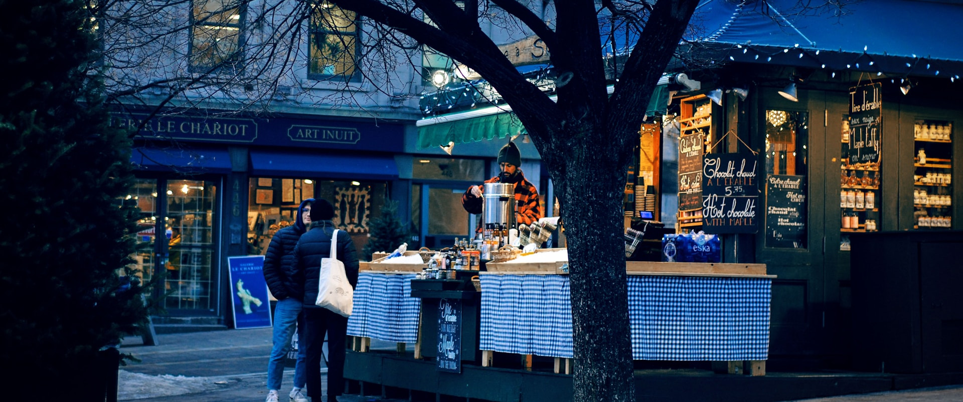 A cozy outdoor hot chocolate stall with a backdrop of charming storefronts.