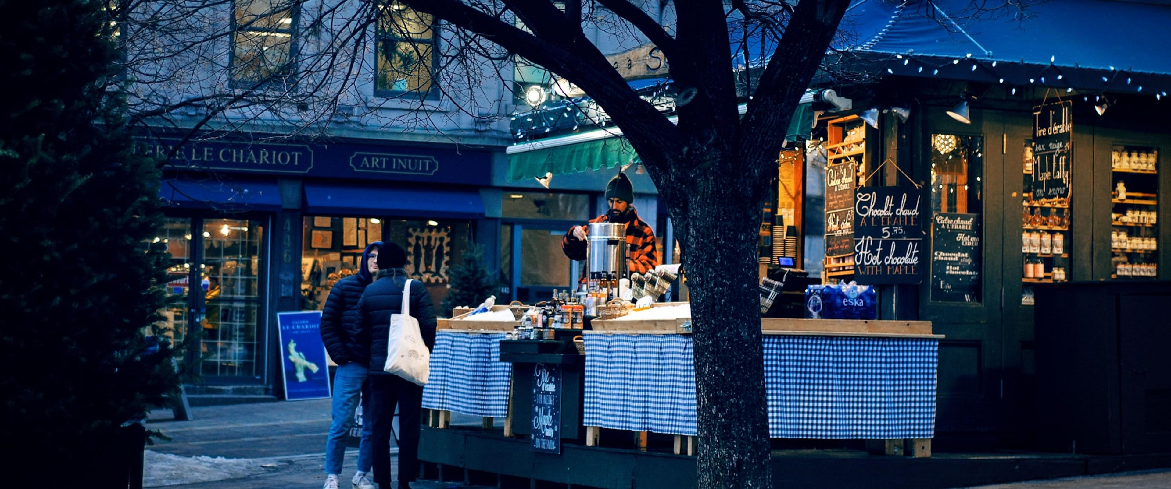 A cozy outdoor hot chocolate stall with a backdrop of charming storefronts.