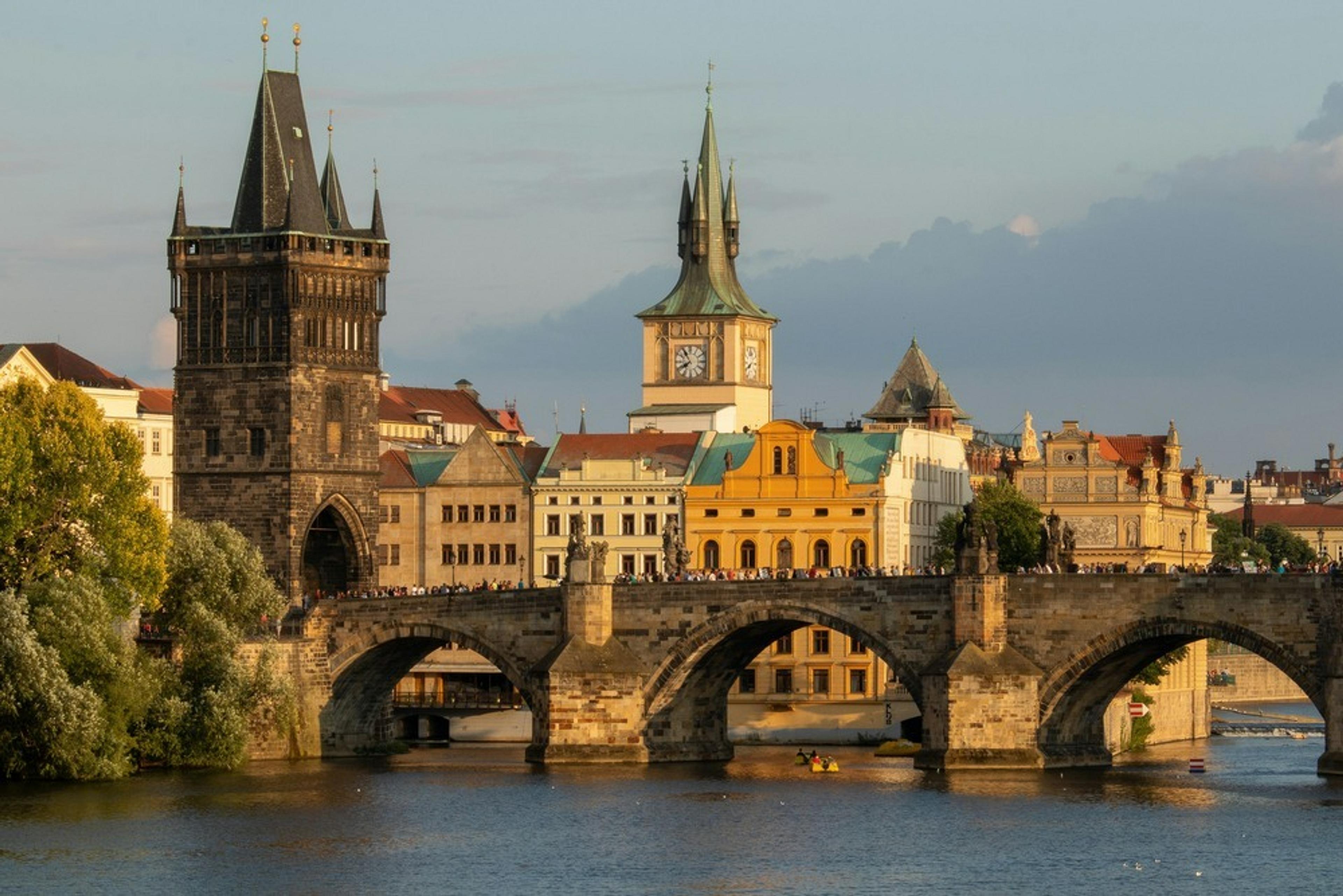 Charles Bridge in Prague spans the Vltava River, surrounded by historic architecture.