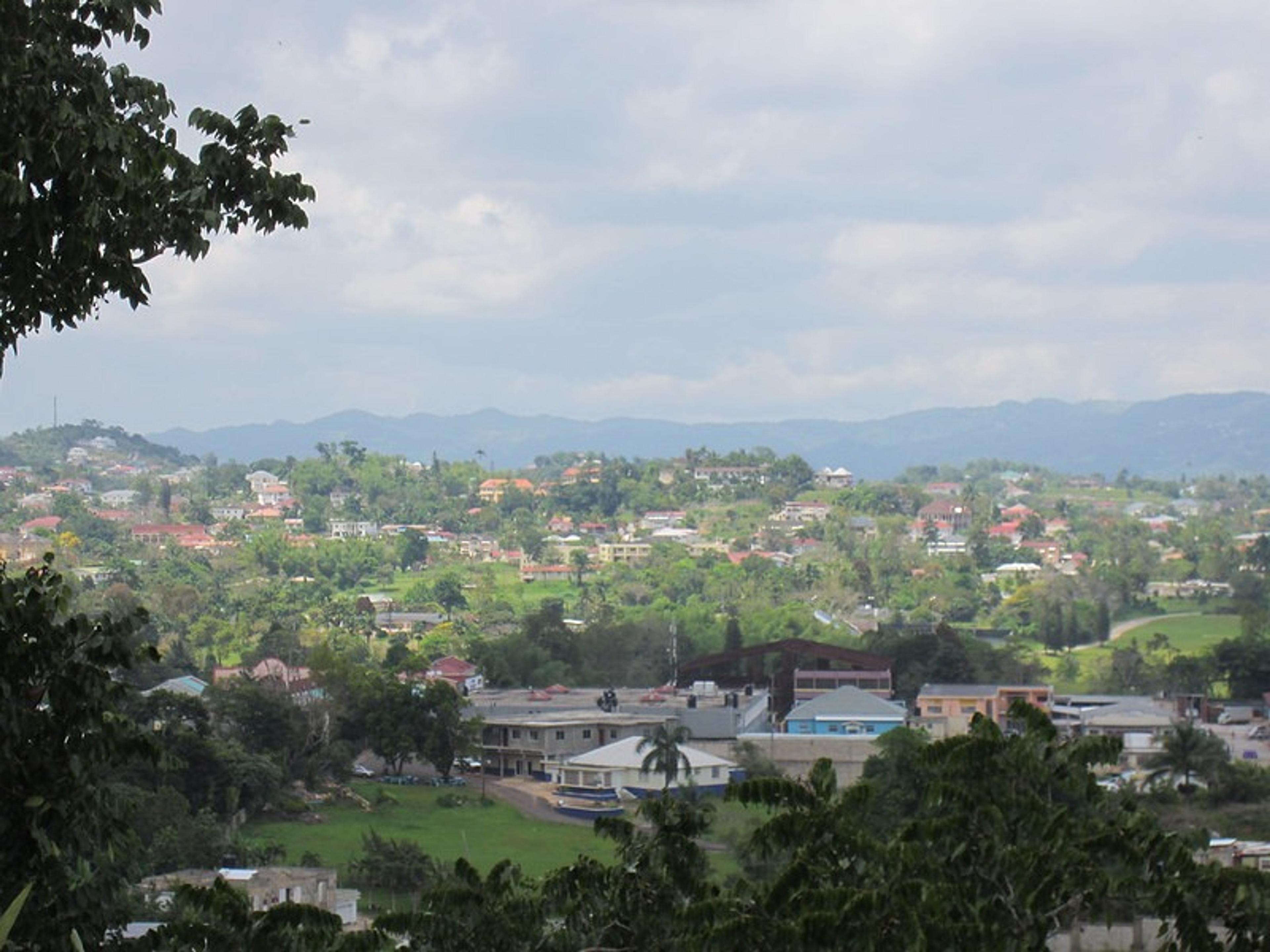 A scenic view of Kampala, Uganda, with lush greenery and scattered buildings against a backdrop of rolling hills.