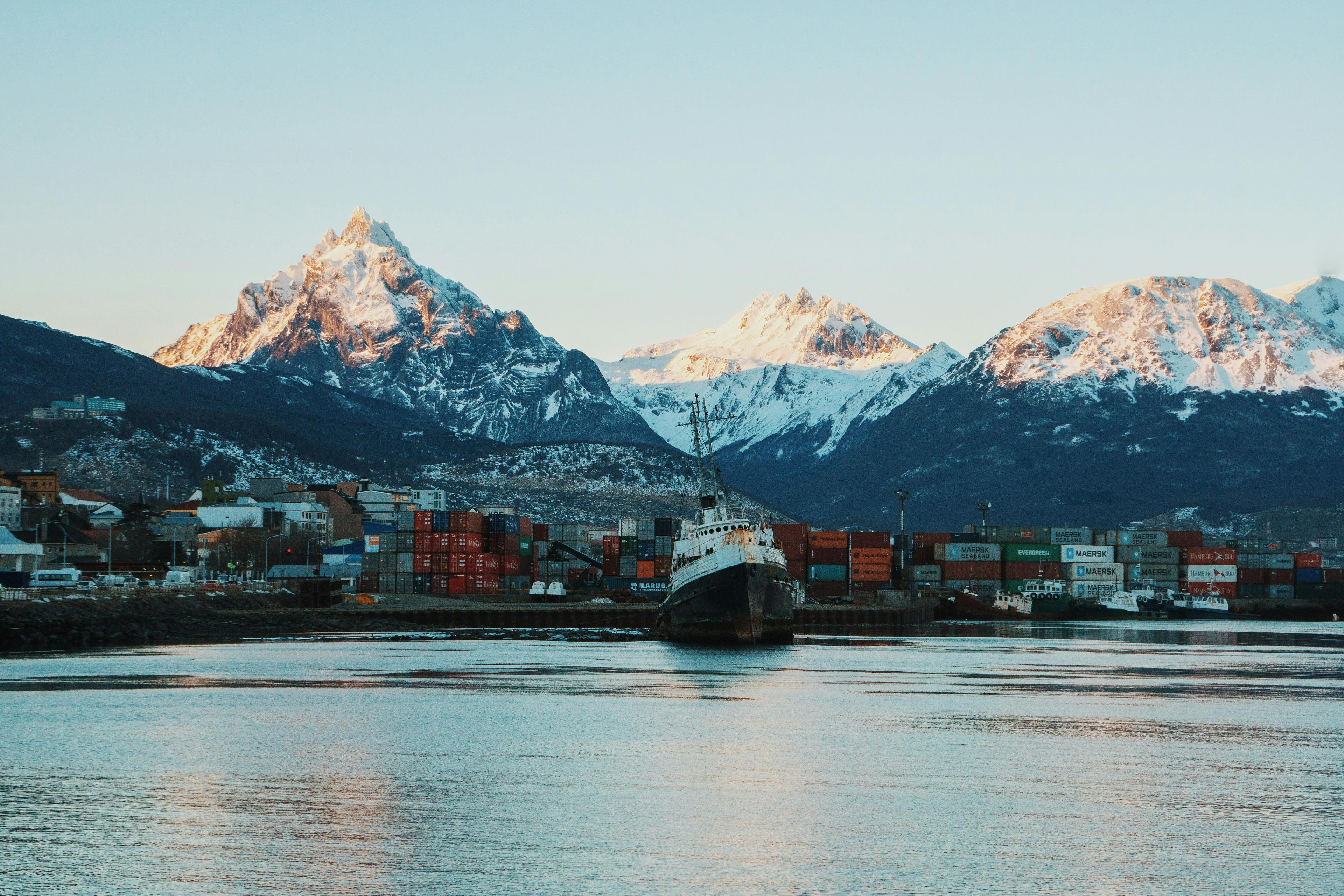 A harbor with stacked shipping containers and a ship set against the backdrop of snow-capped mountains in Ushuaia, Argentina.