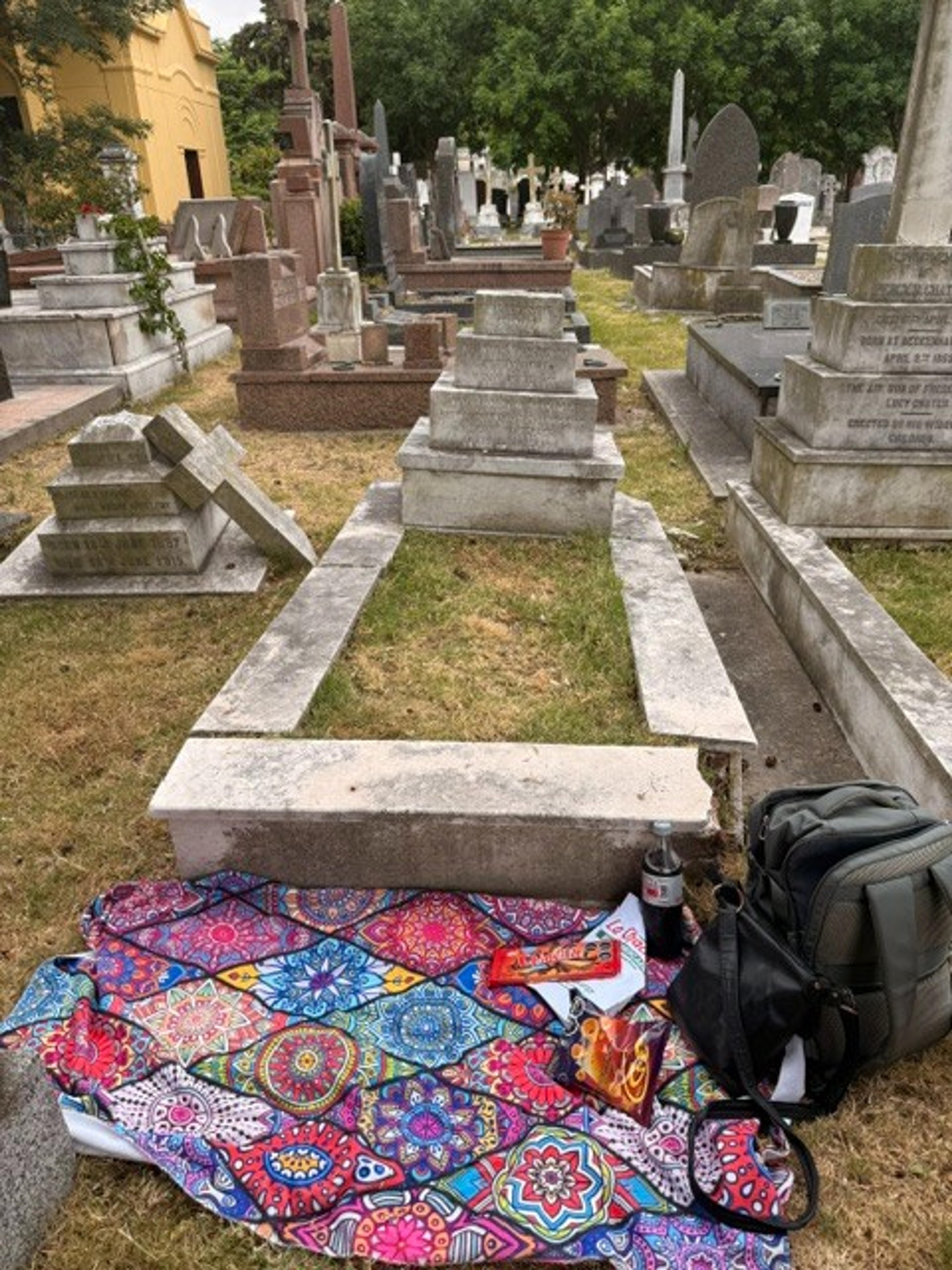 A colorful picnic setup is laid out among the tombstones in the cemetery of Cañon de San Lorenzo, highlighting a unique contrast between vibrant life and solemnity.