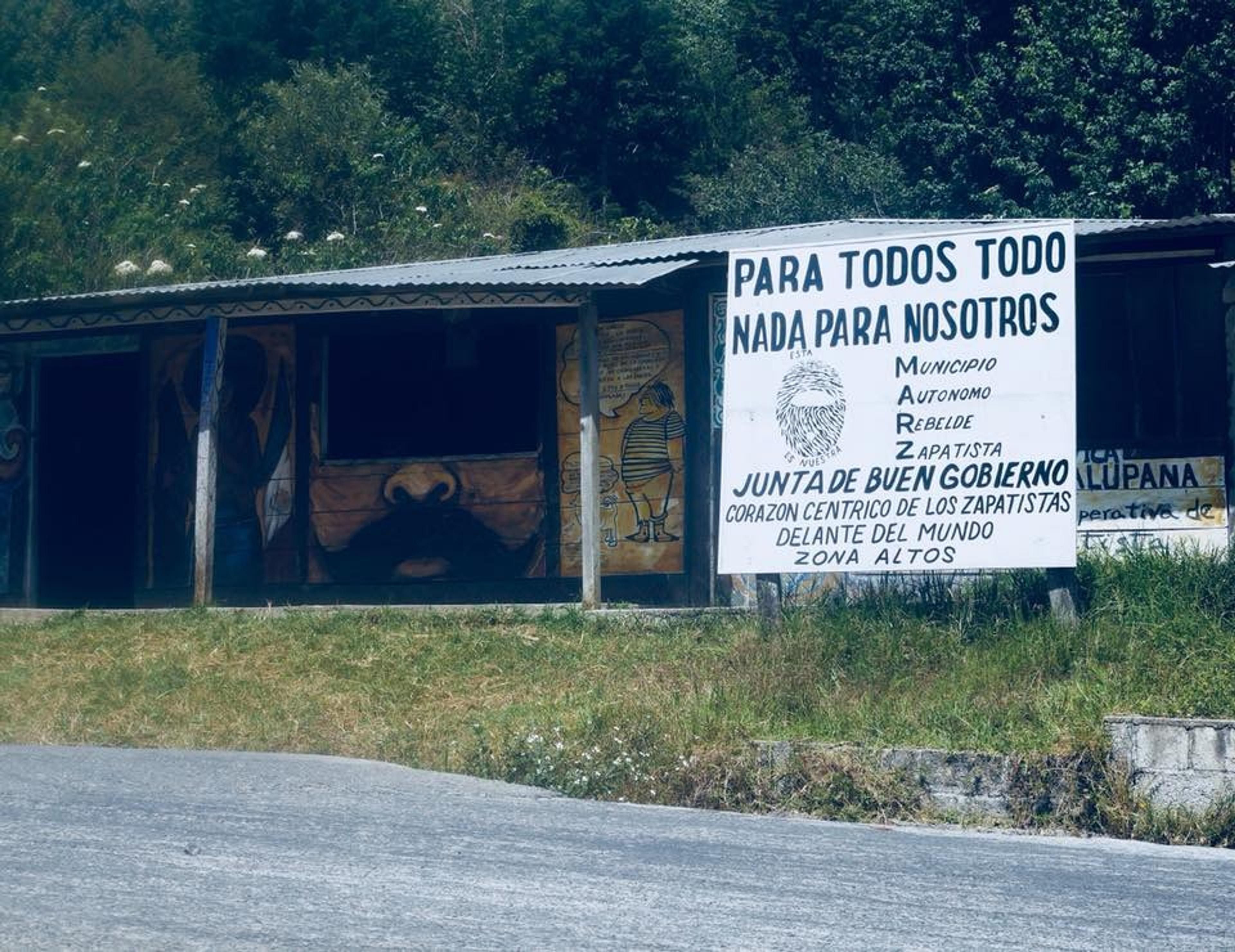 A building in the Zapatista area of Chiapas, Mexico, features murals and a prominent sign advocating for the Junta de Buen Gobierno.