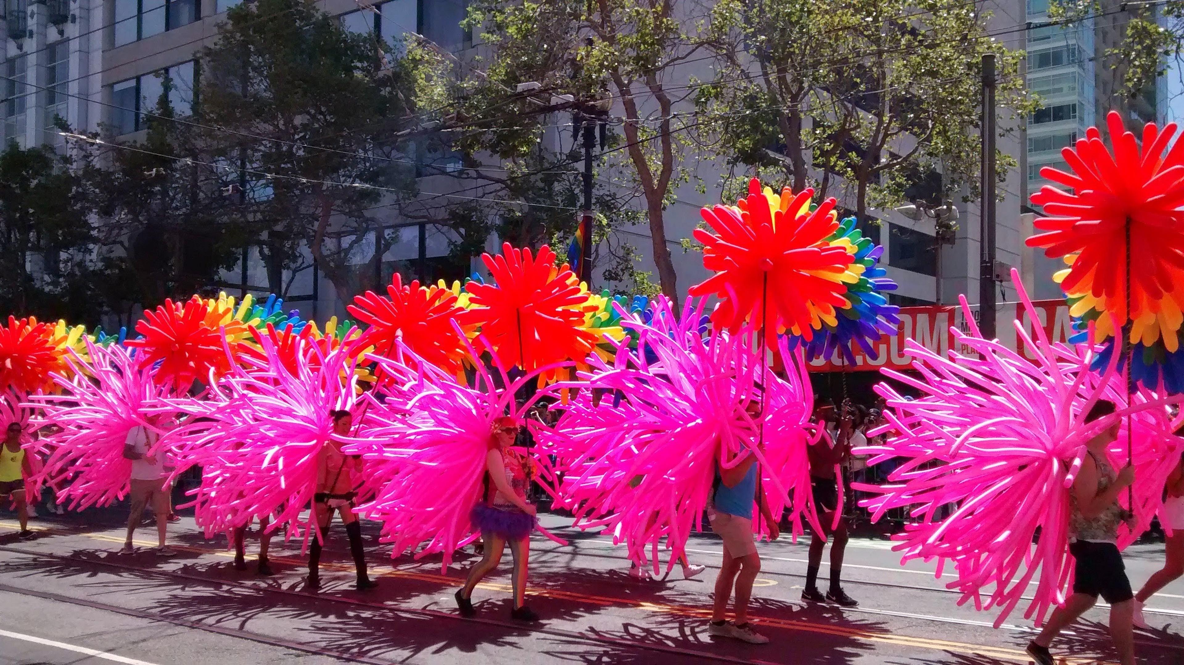 A vibrant parade with performers wearing colorful balloon costumes takes place in San Francisco during pride